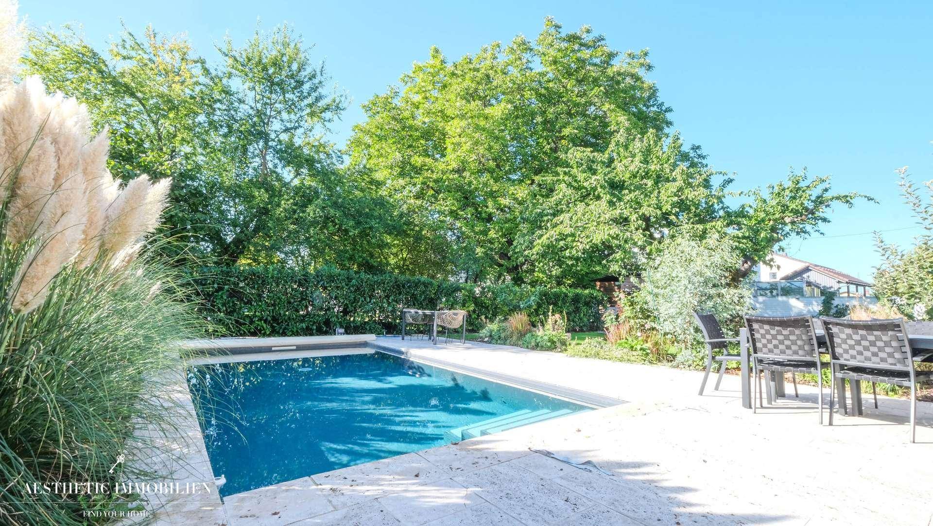 Außenbereich mit Swimmingpool, gepflasterter Terrasse und üppiger Bepflanzung.