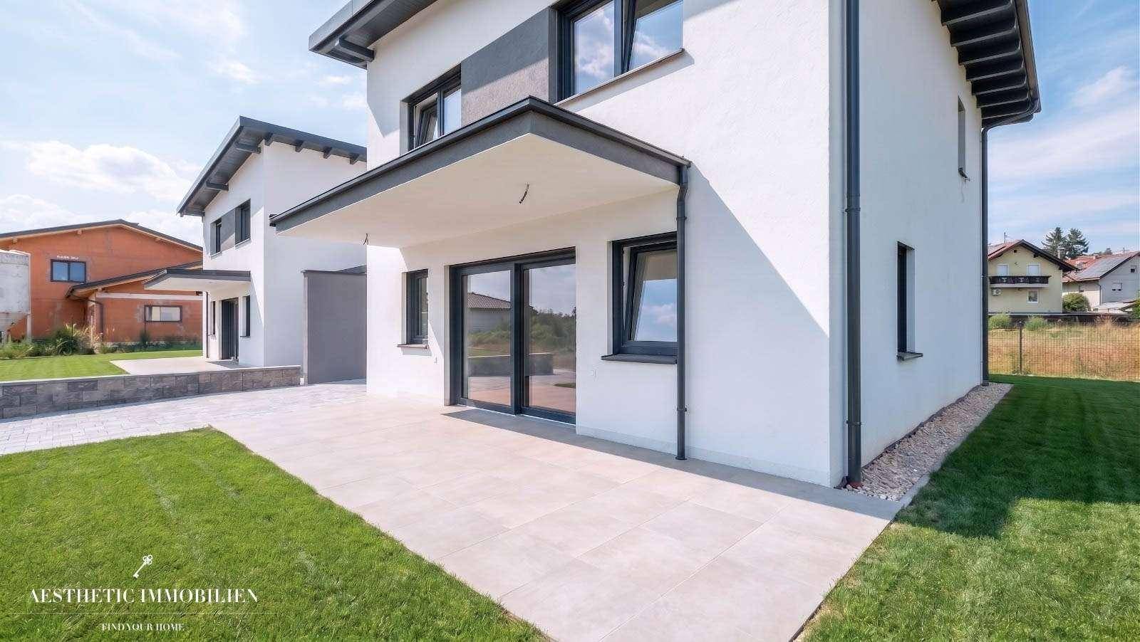 Sonniger Terrassenbereich mit Fliesenboden und angrenzender Rasenfläche.