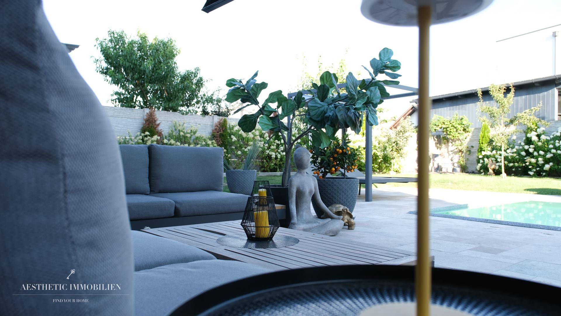 Gemütlicher Außenbereich mit Lounge-Möbeln, Blick auf den Garten und den Pool.