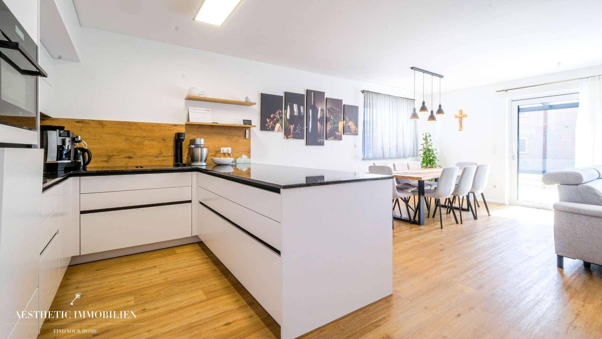 Moderne Küche mit dunkler Arbeitsplatte, Essbereich und Zugang zur Terrasse.