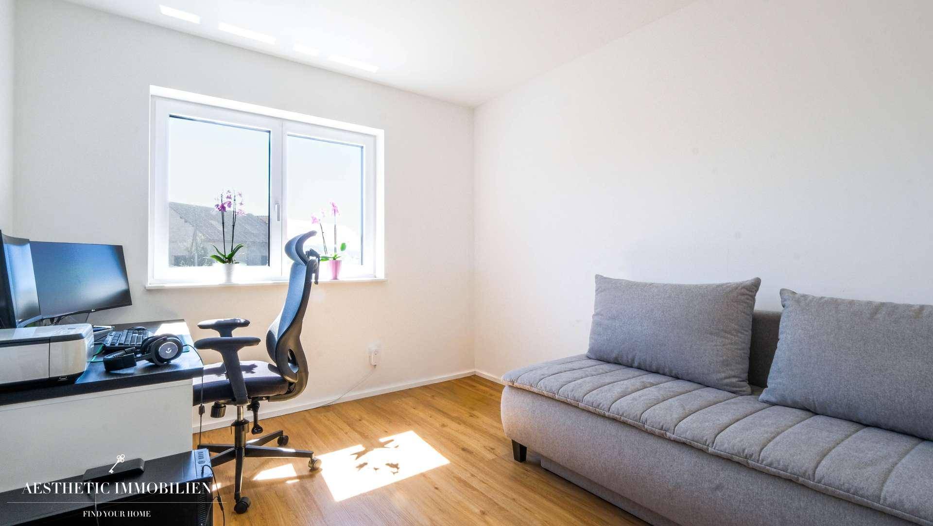 Helles Arbeitszimmer mit Schreibtisch, Bürostuhl und Sofa, ideal für Home-Office.