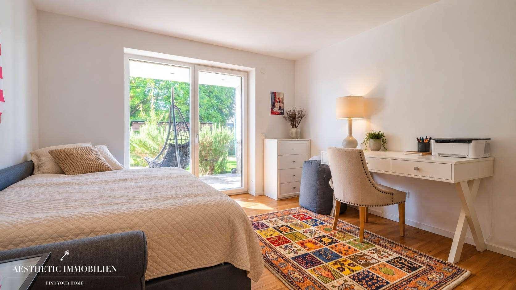 Gemütliches Schlafzimmer mit Schreibtisch, farbenfrohem Teppich und Zugang zum Garten.