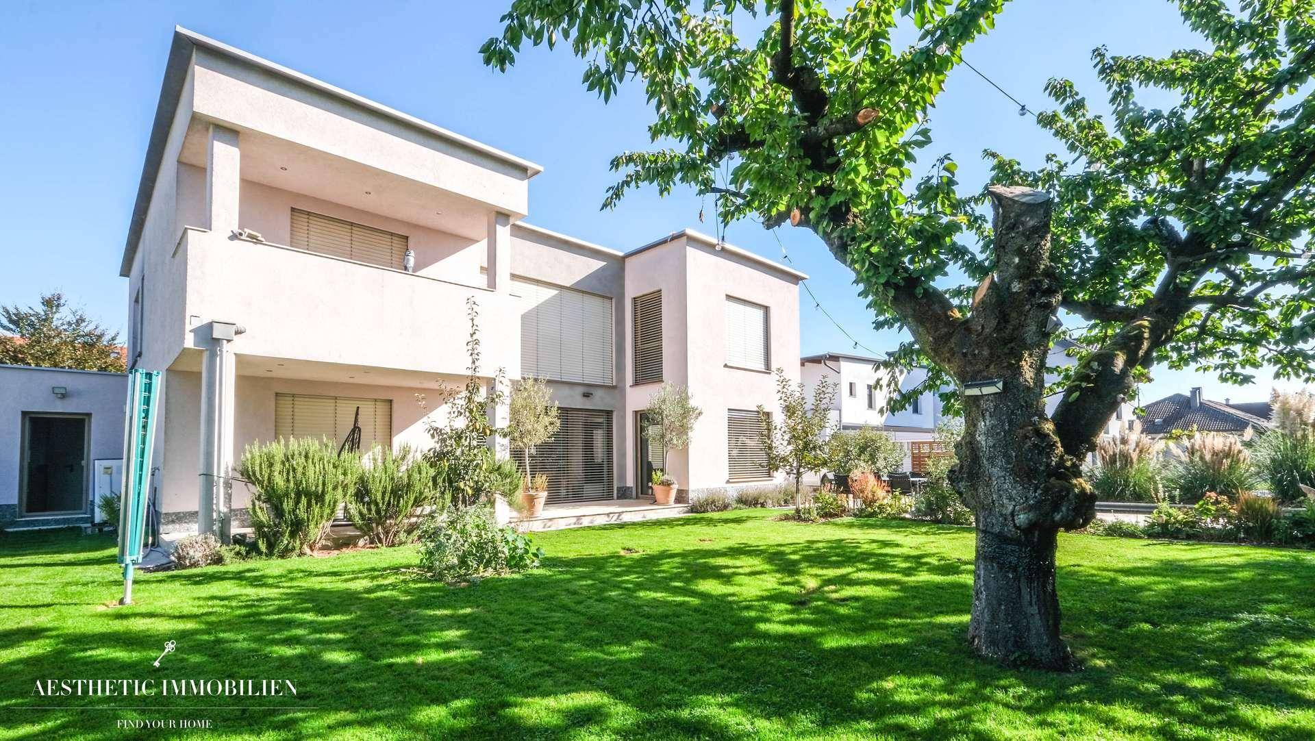Rückansicht des modernen Hauses mit Garten, Balkonen und großen Fenstern.