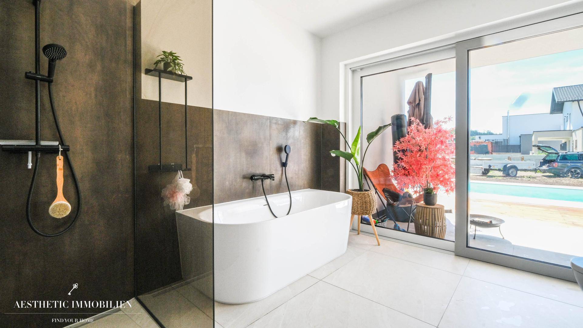 Modernes Badezimmer mit freistehender Badewanne, begehbarer Dusche und großen Fenstern.
