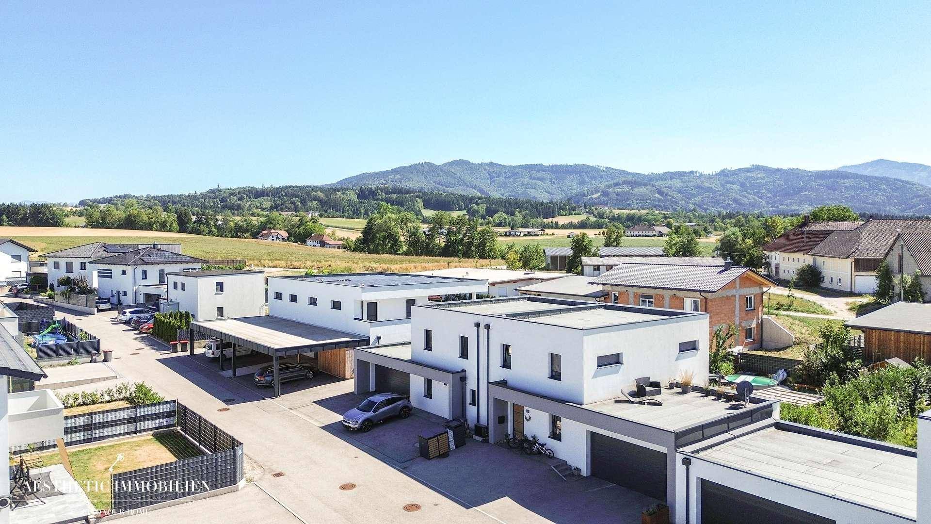 Weitläufiger Blick über die Wohngegend mit modernen Häusern und grünen Hügeln.