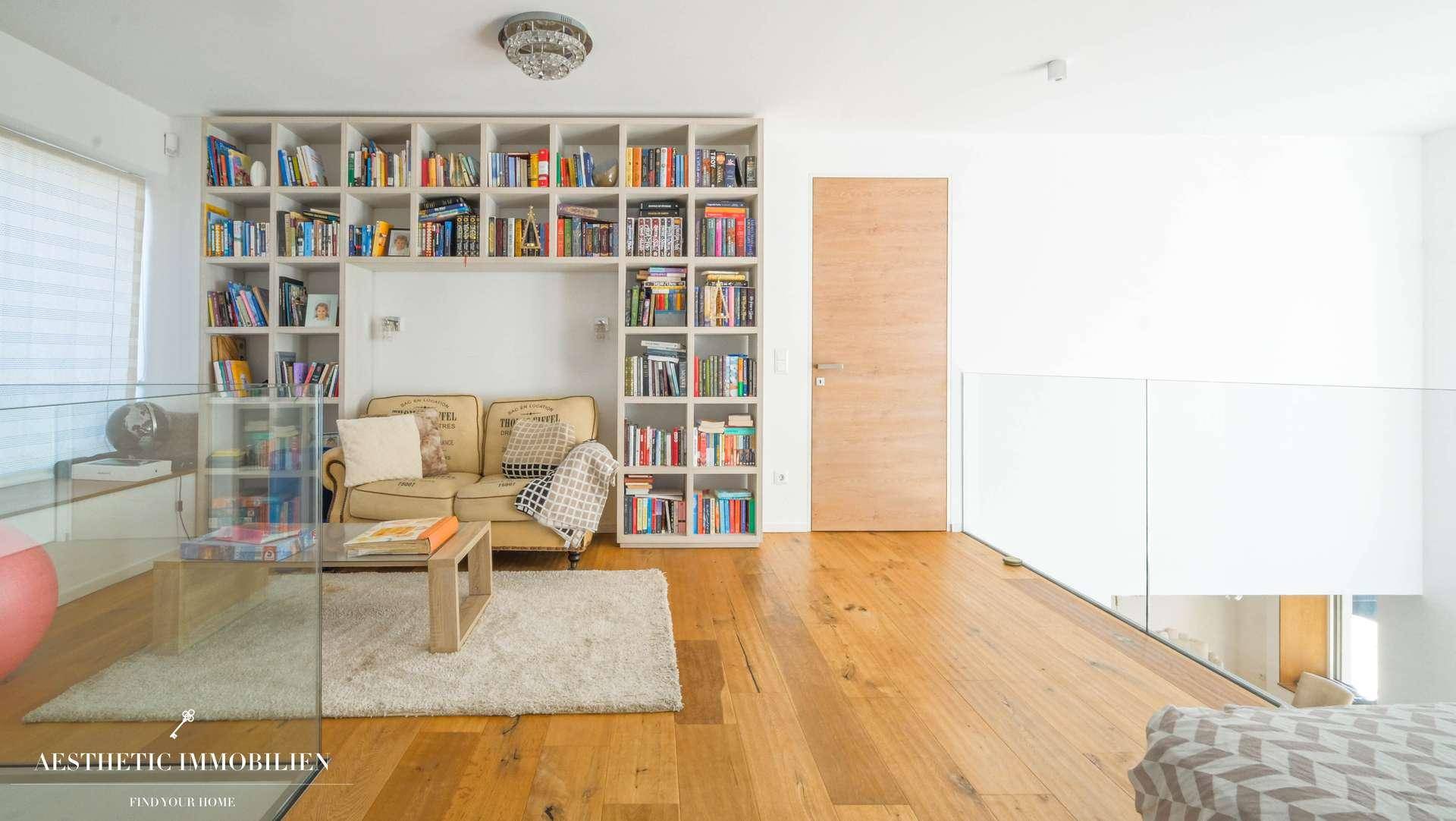 Gemütliche Galerie mit Bücherregal, Sofa und Blick auf den unteren Wohnbereich.