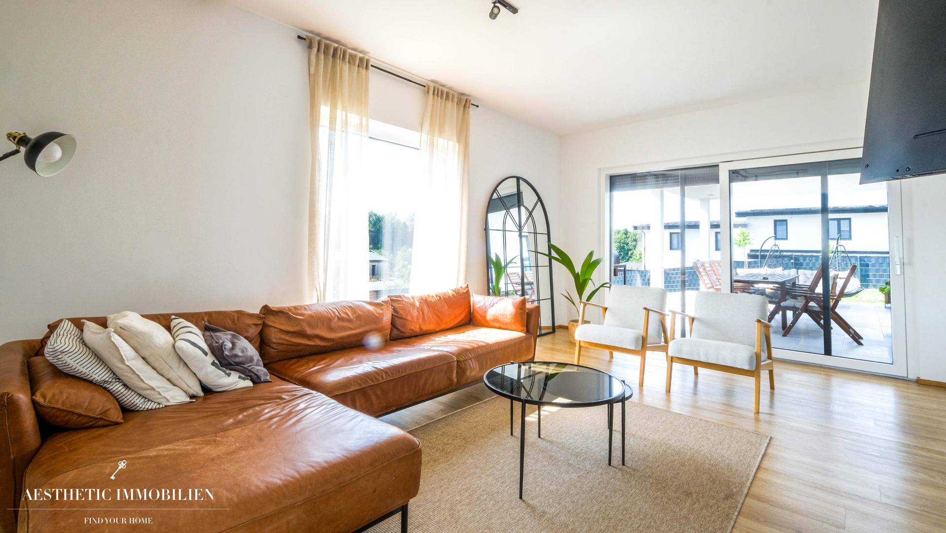 Gemütliches Wohnzimmer mit Ledersofa und direktem Zugang zur großen Außenterrasse.