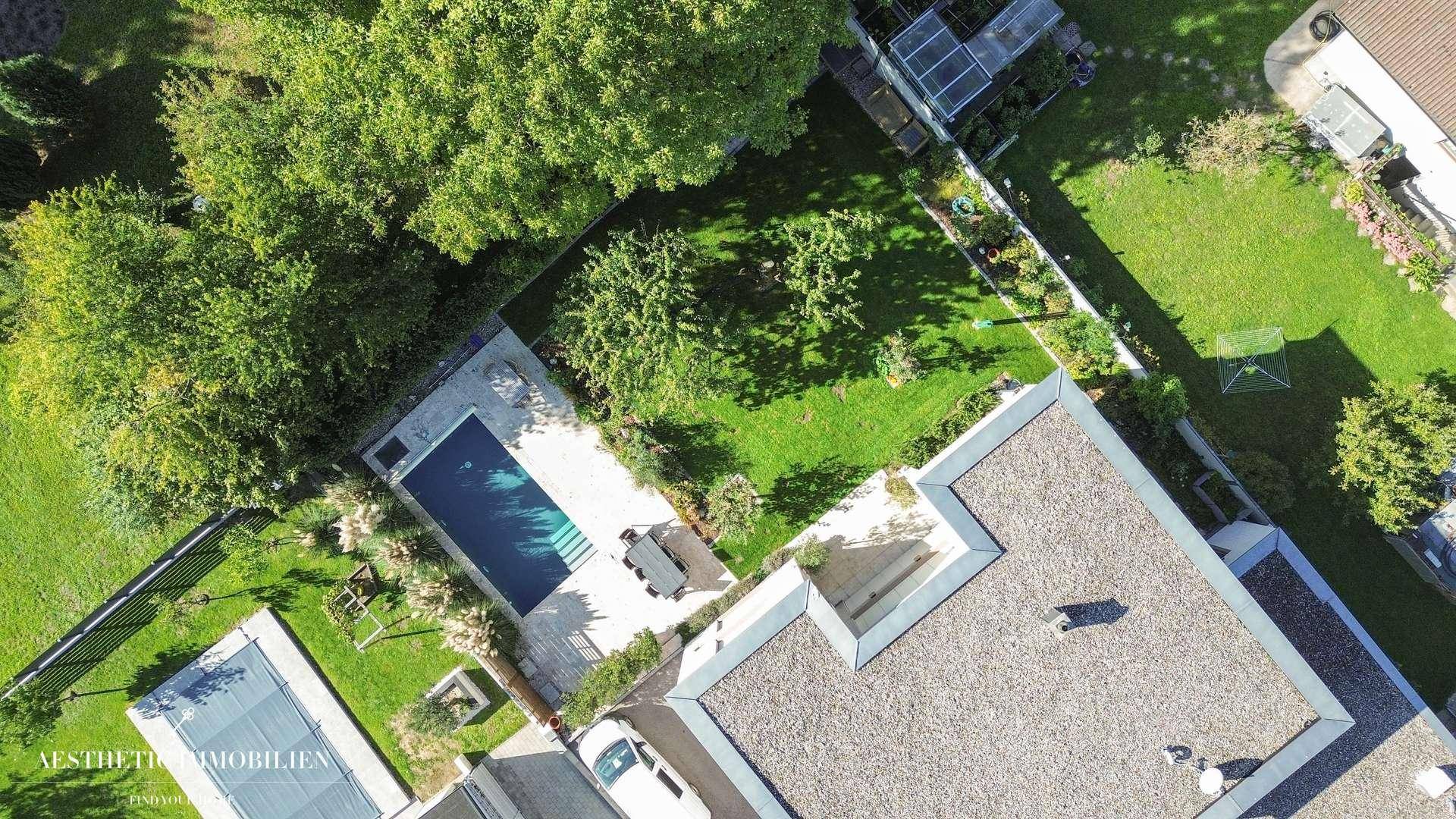 Luftaufnahme des Anwesens mit großem Garten, Pool und Flachdach.