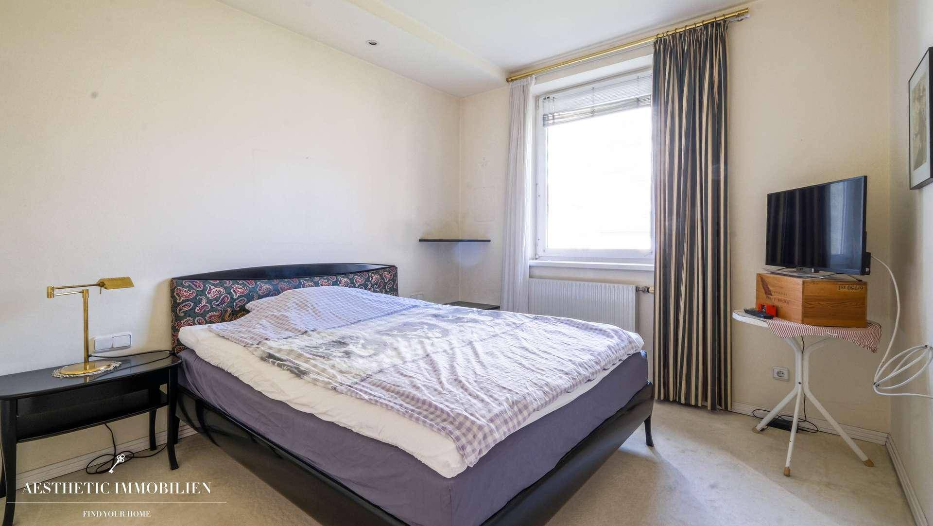 Schlafzimmer mit Doppelbett, Teppichboden und Fenster mit Vorhängen.