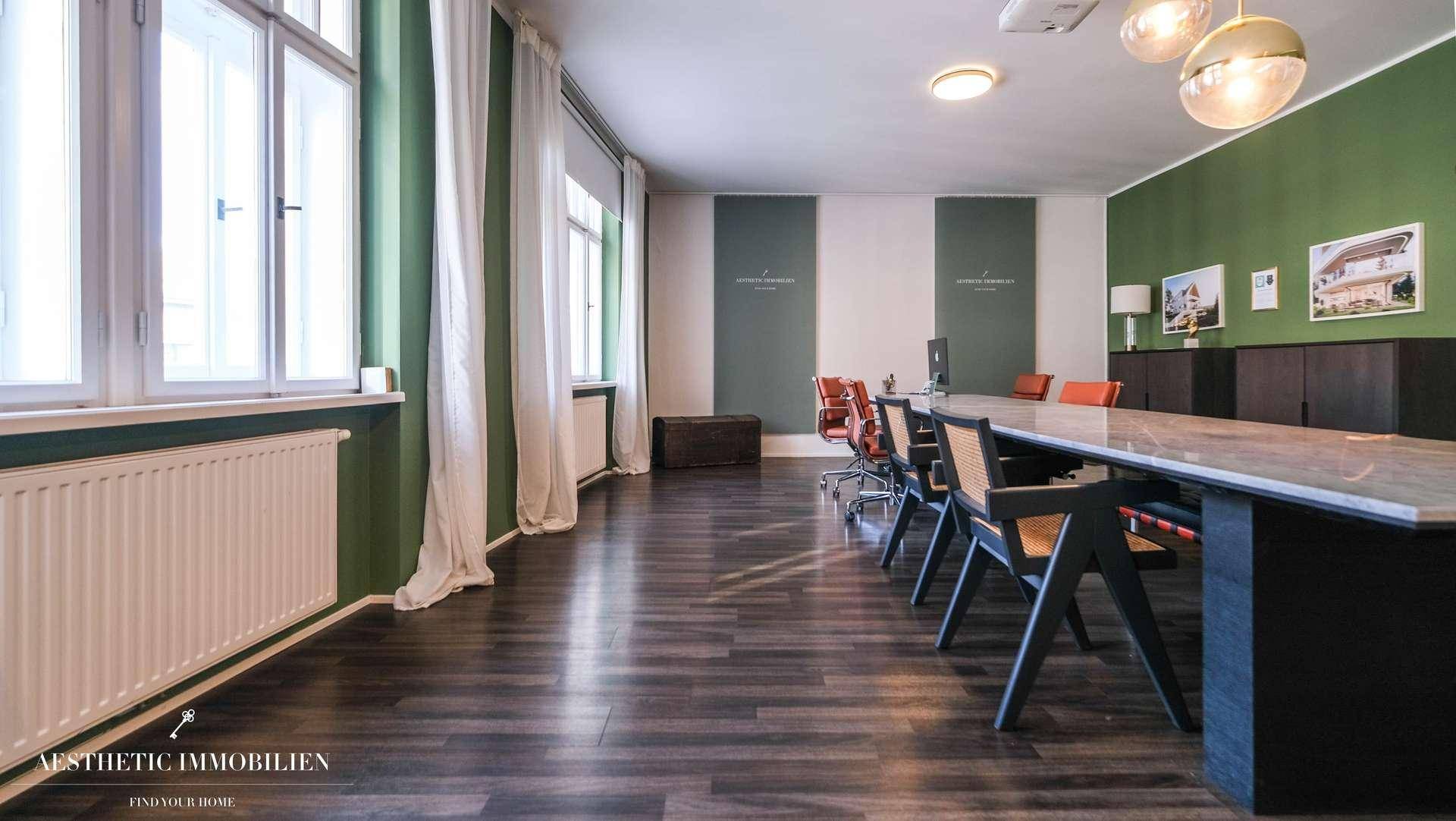 Langer Konferenzraum mit dunklem Holzboden, großen Fenstern und minimalistischer Einrichtung, ideal für Besprechungen.