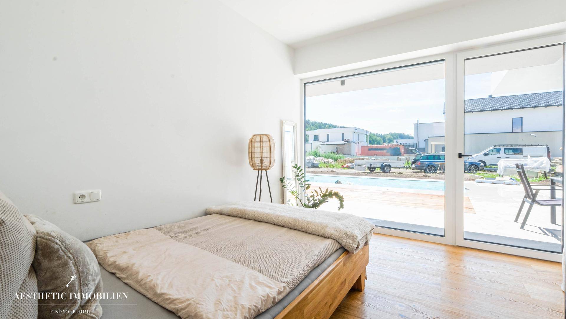 Gemütliches Schlafzimmer mit Holzbett, Holzboden und Blick auf den Außenbereich.