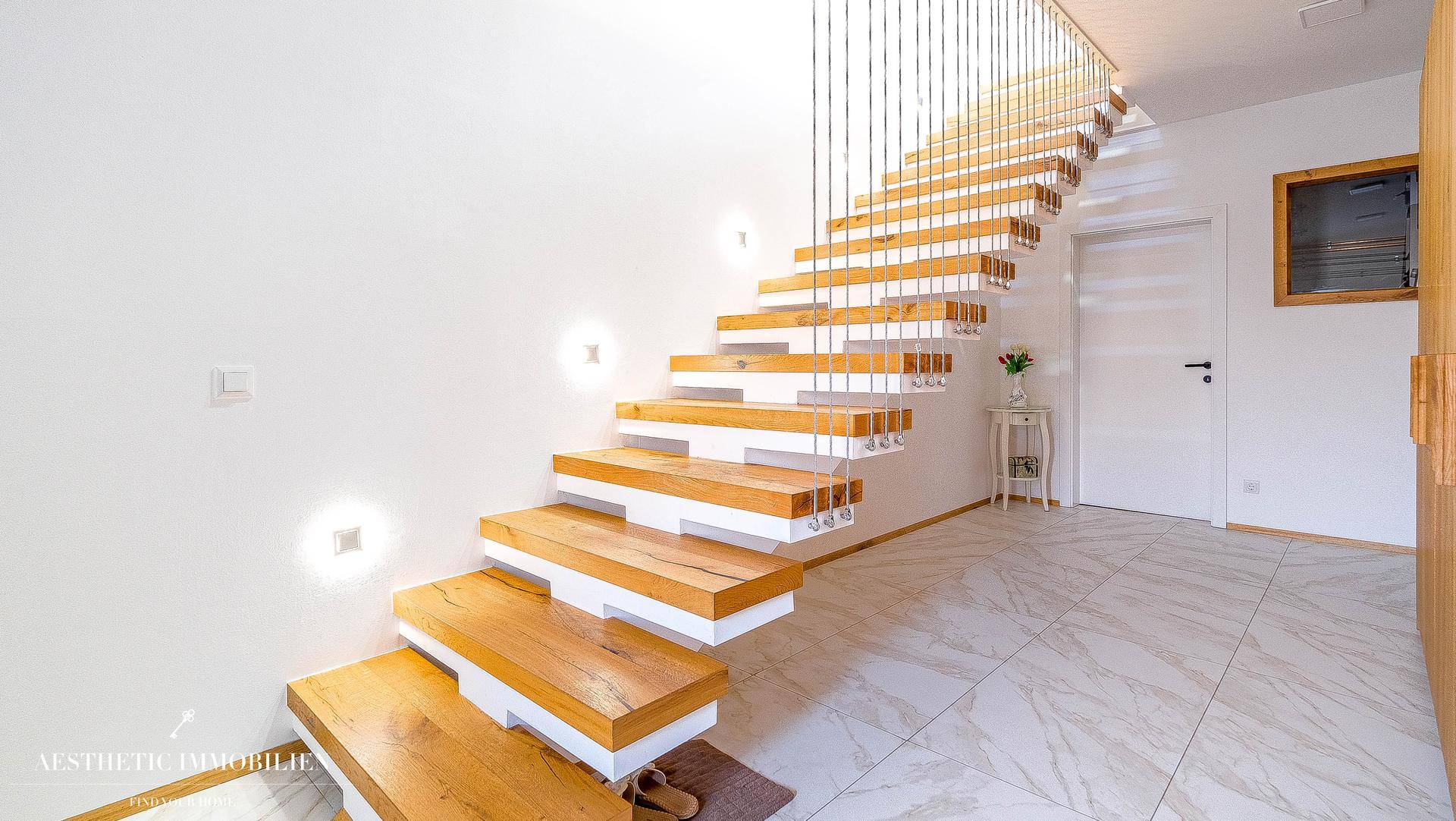 Moderner Flur mit schwebender Holztreppe und eleganten Marmorfliesen.