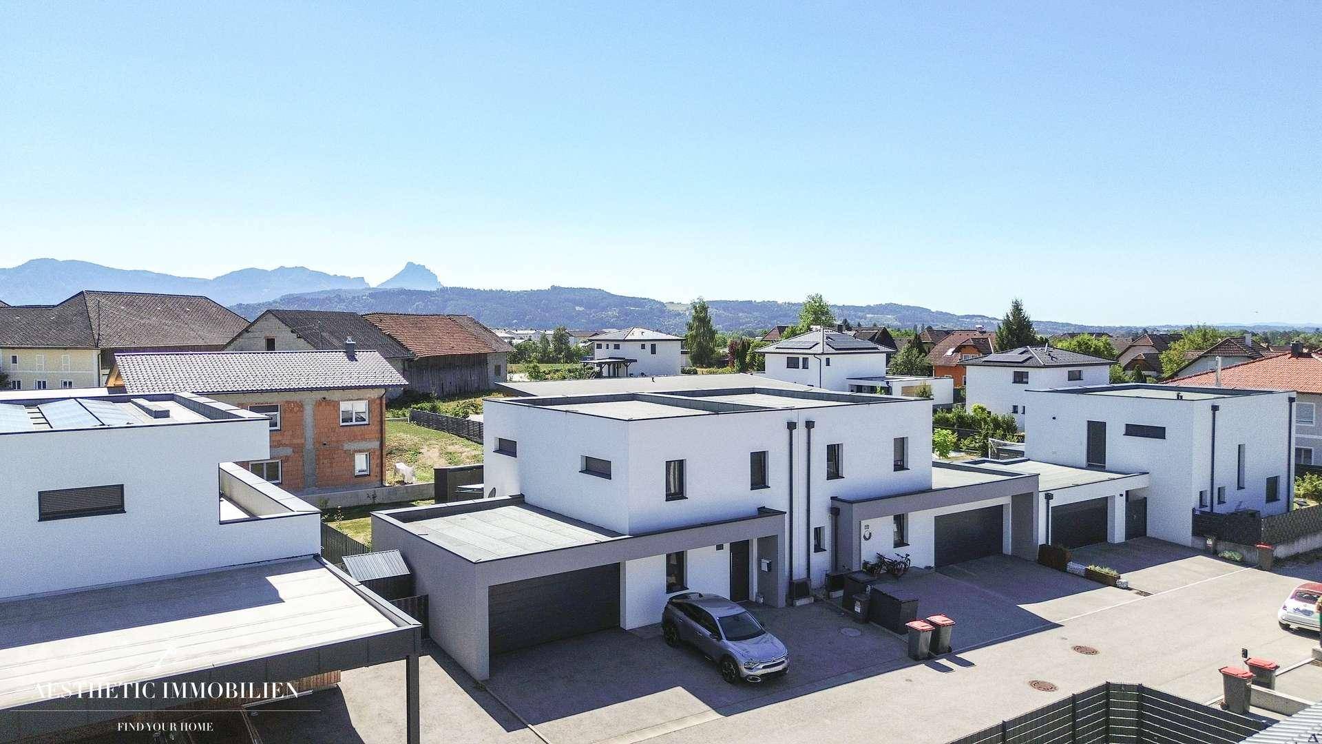 Panoramablick auf die Wohnsiedlung mit modernen Häusern und Bergkulisse im Hintergrund.
