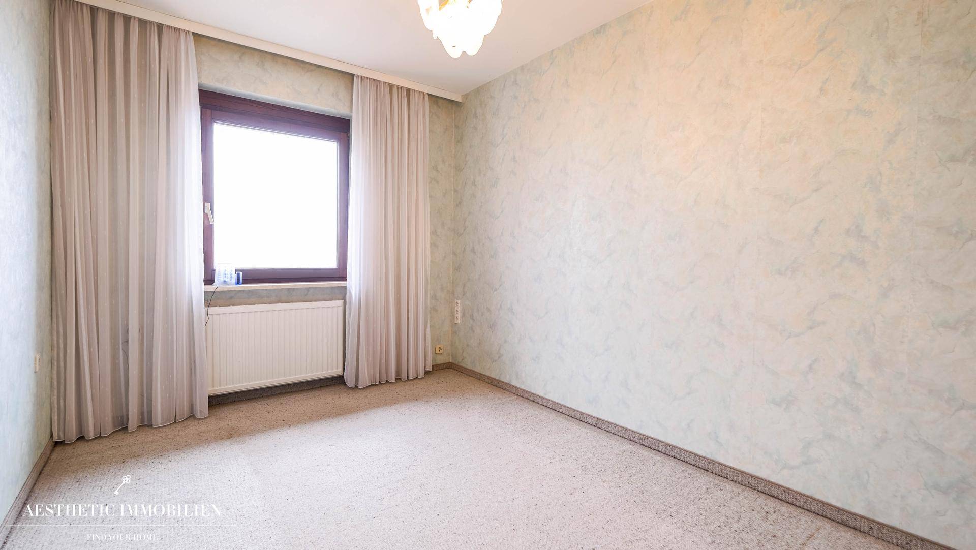 Schlafzimmer mit Teppichboden, Fenster und heller Wandgestaltung.