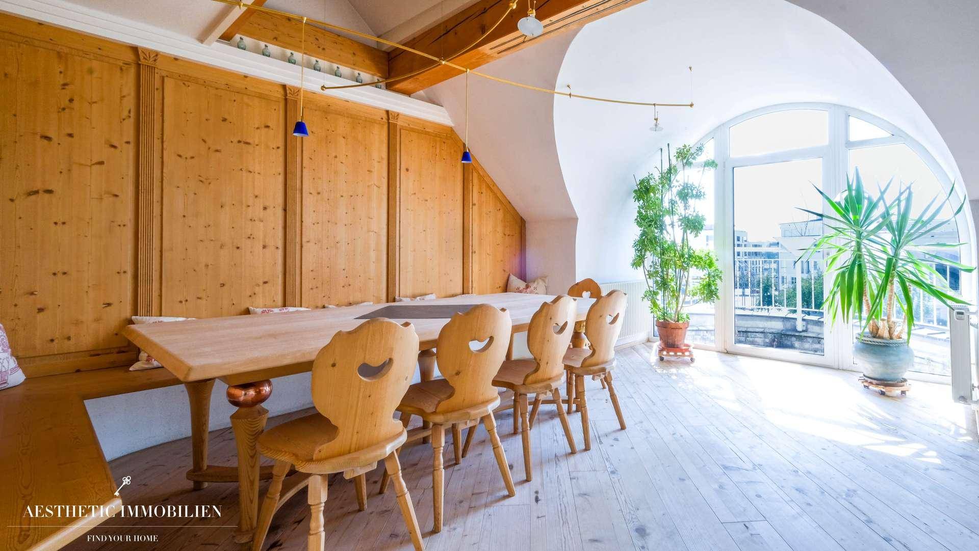 Heller Essbereich mit Holztäfelung, Holzbalken und großem Rundbogenfenster.