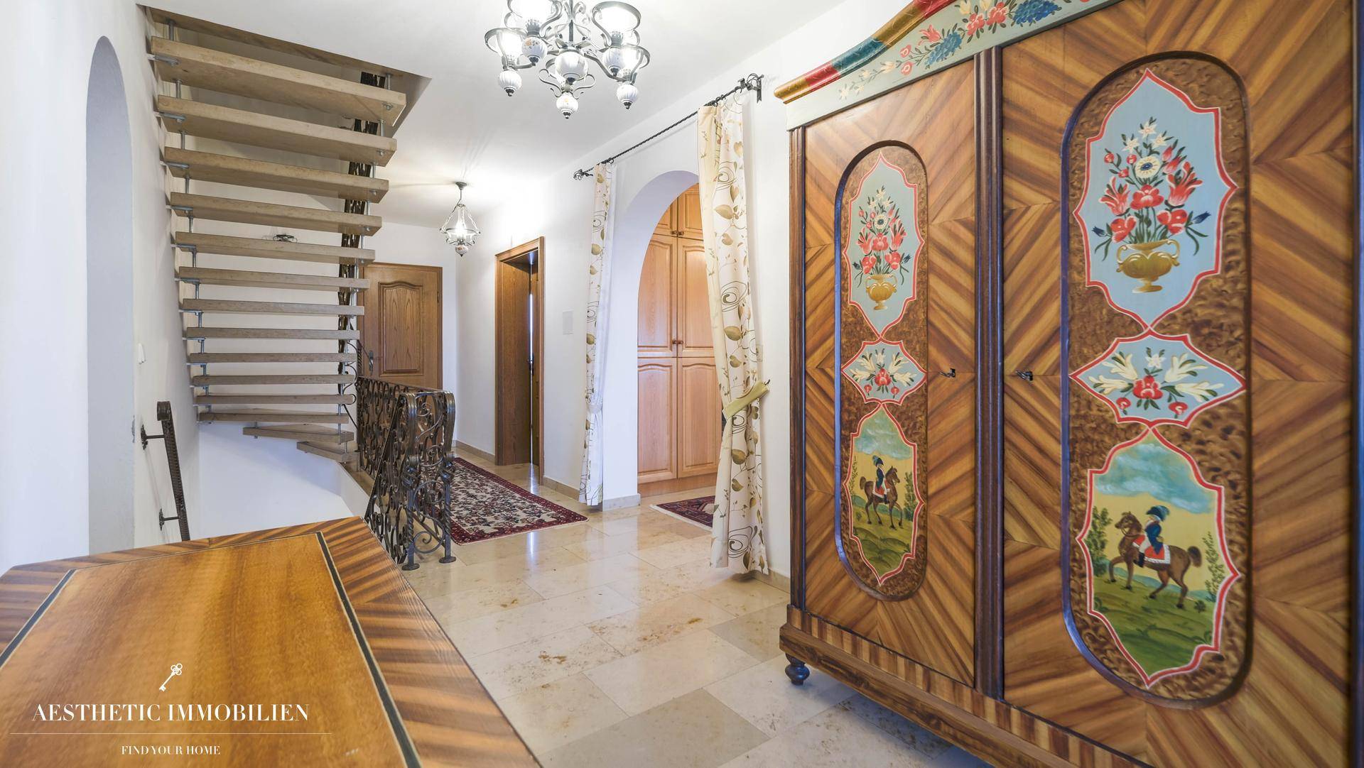 Geräumiger Flur mit Steinfliesen, Holztreppe und traditionellem Schrank.