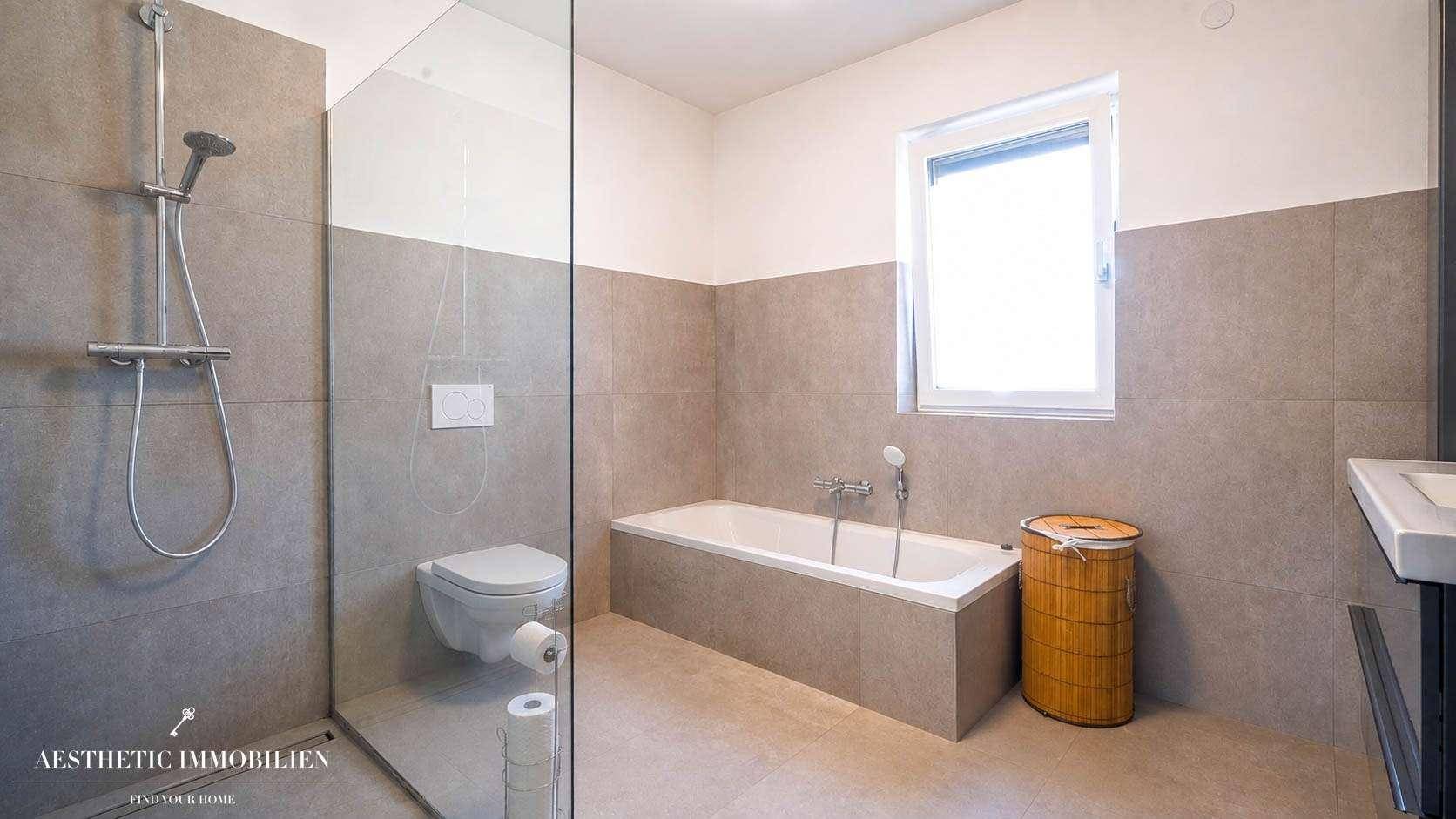 Modernes Badezimmer mit Badewanne, ebenerdiger Dusche und Wand-WC.