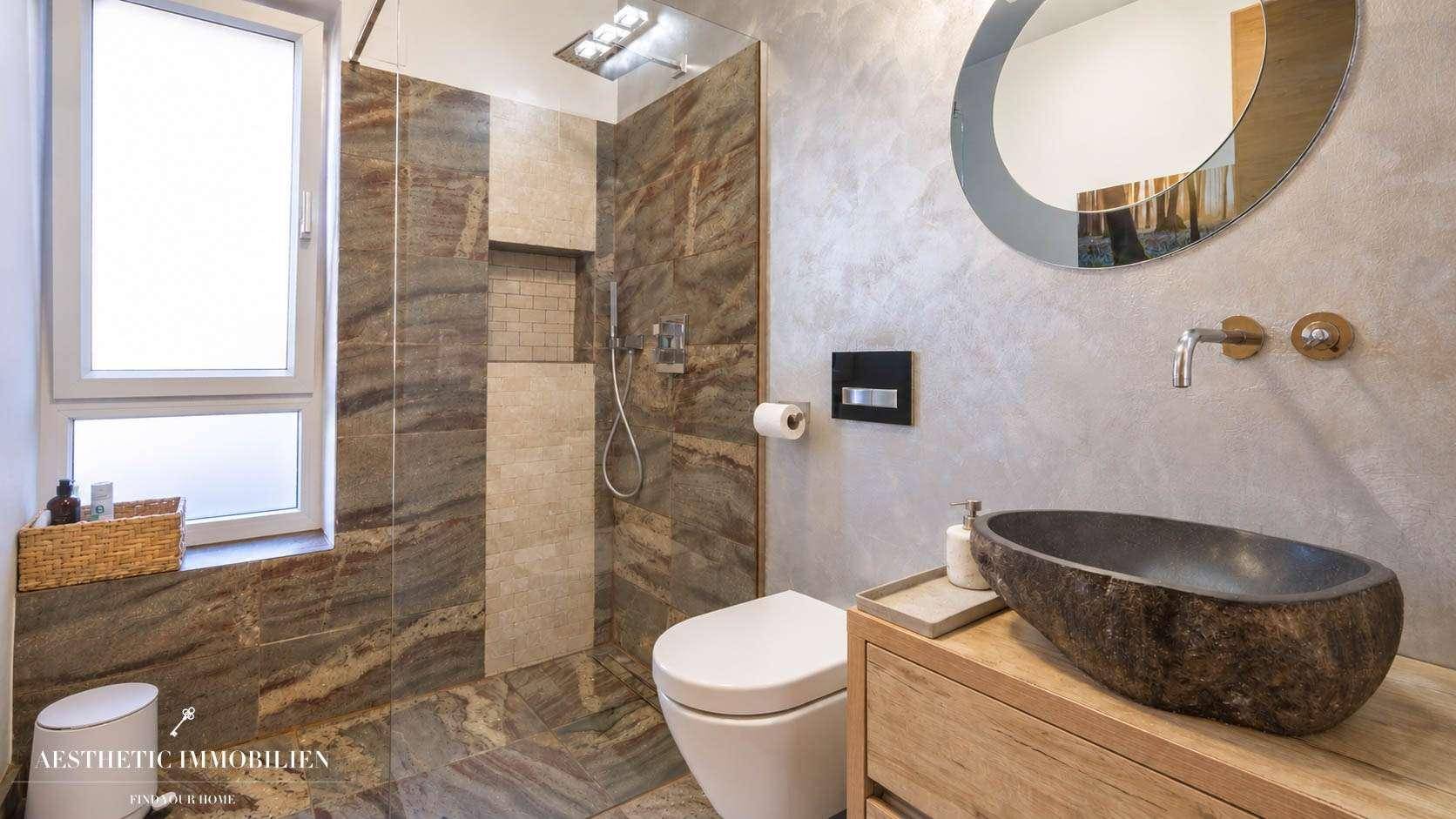 Modernes Badezimmer mit begehbarer Dusche, Natursteinfliesen und einzigartigem Waschbecken.