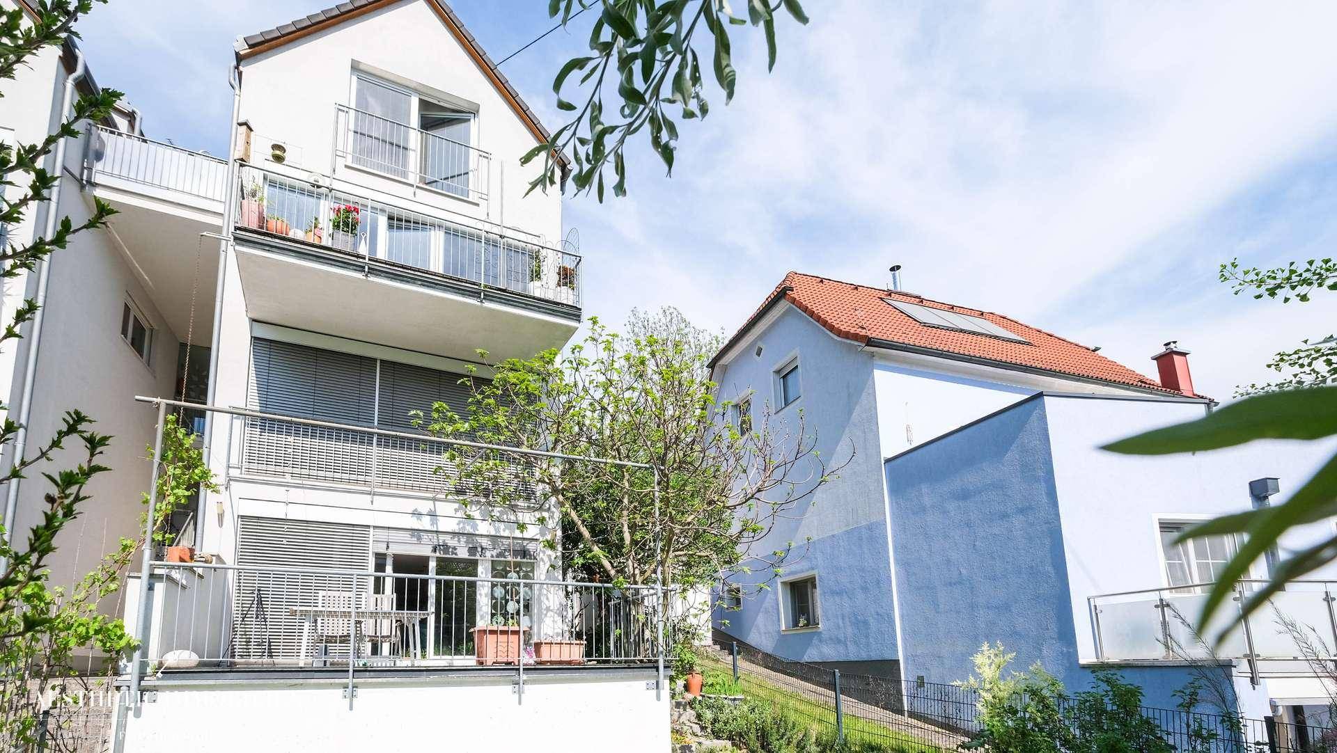 Außenansicht von zwei Wohnhäusern, eines mit Balkonen und das andere mit blauer Fassade.