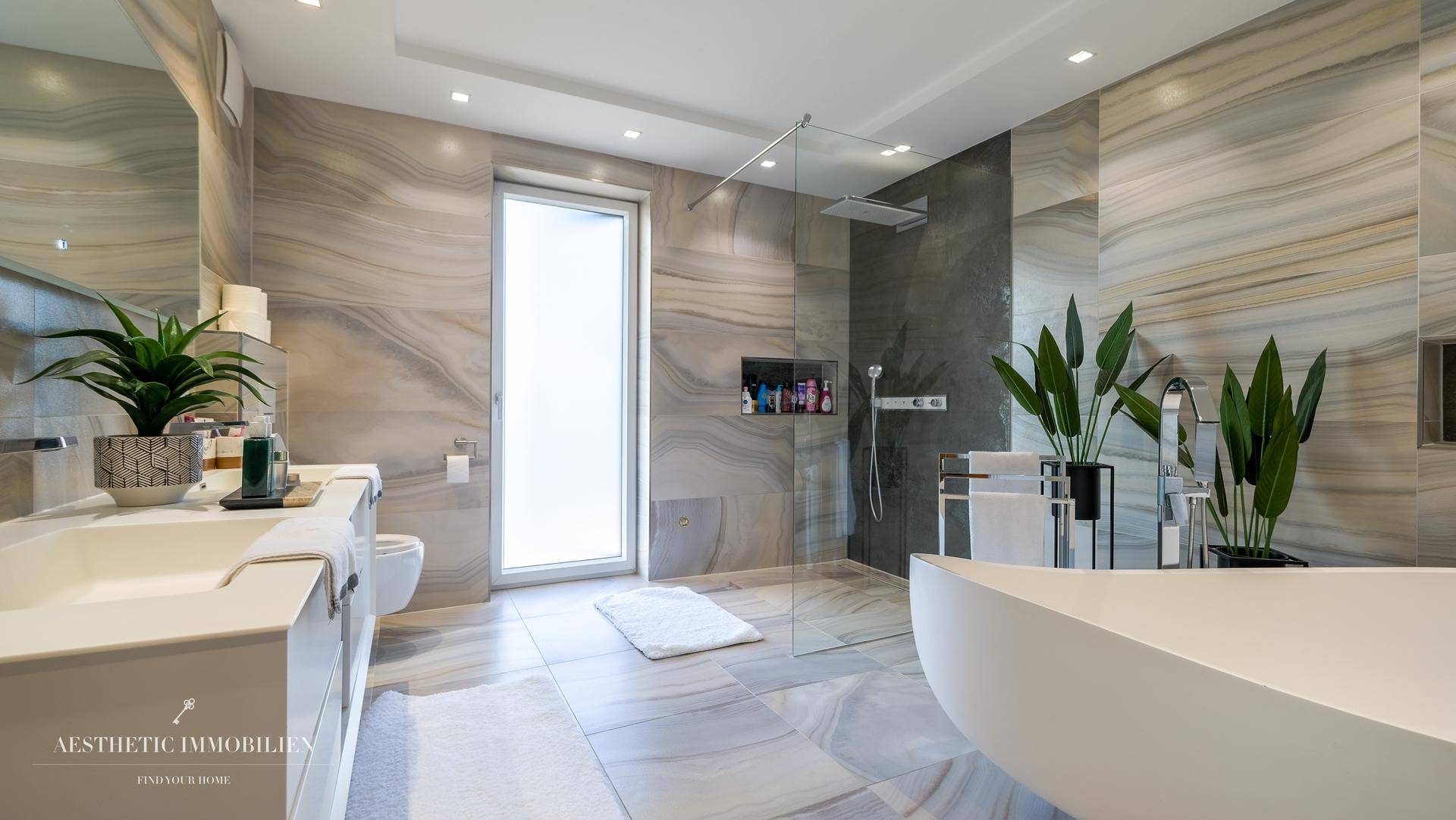 Luxuriöses Badezimmer mit freistehender Badewanne, großer Dusche und Marmorfliesen.