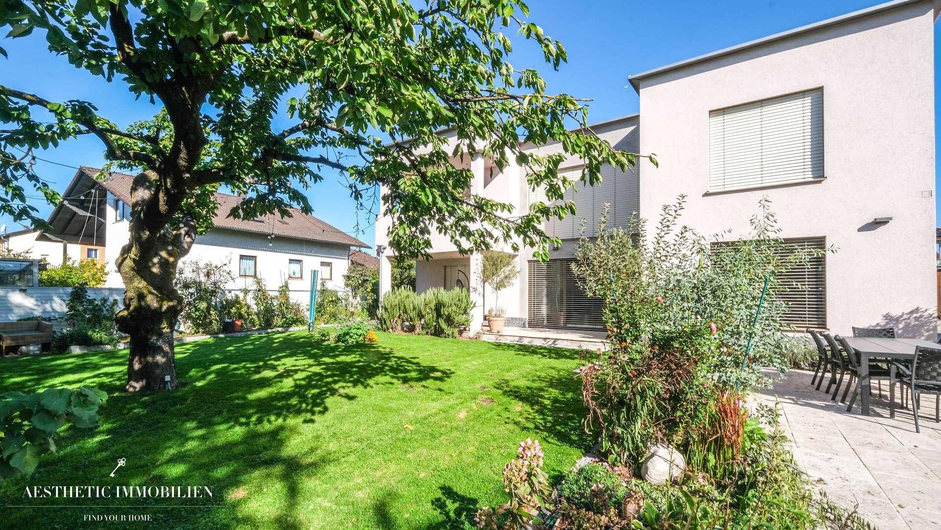 Gepflegter Garten mit Rasenfläche, Bäumen und Terrasse am Haus.