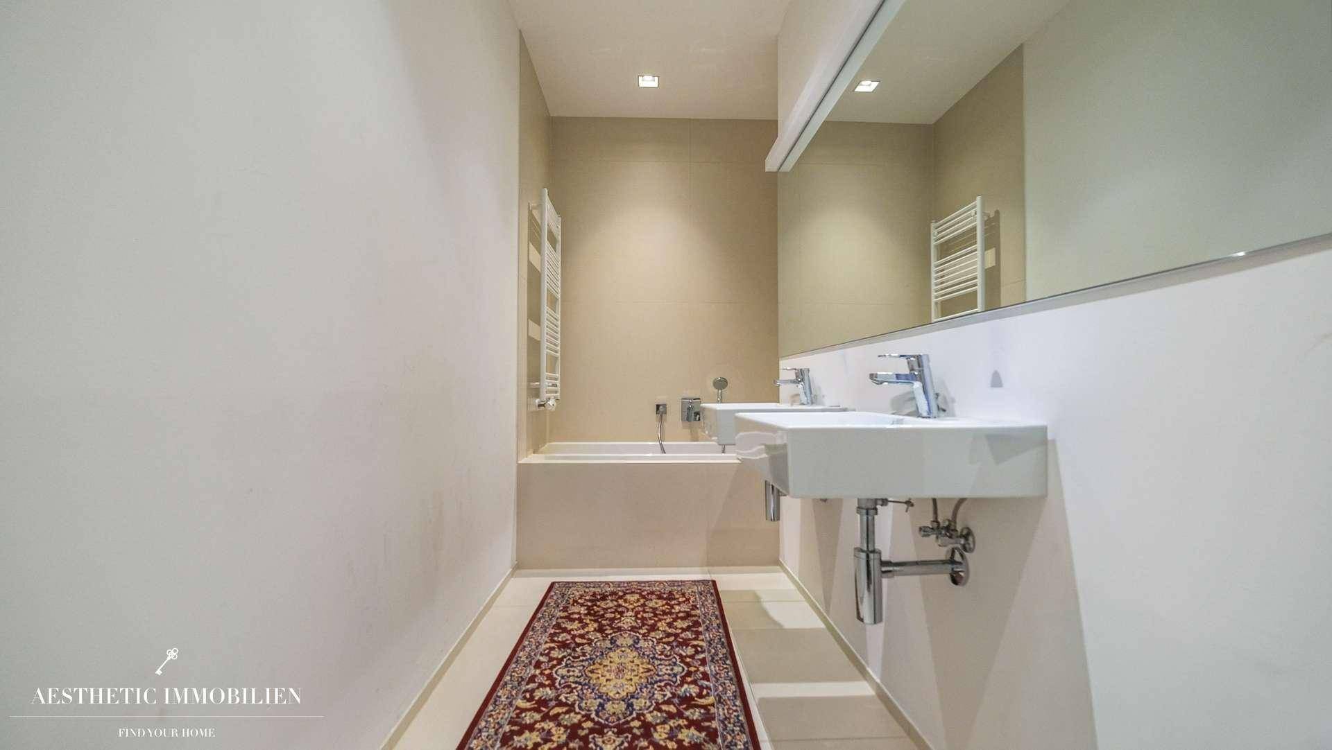 Modernes Badezimmer mit Doppelwaschbecken, großer Badewanne und einem Wandspiegel, der den Raum vergrößert.