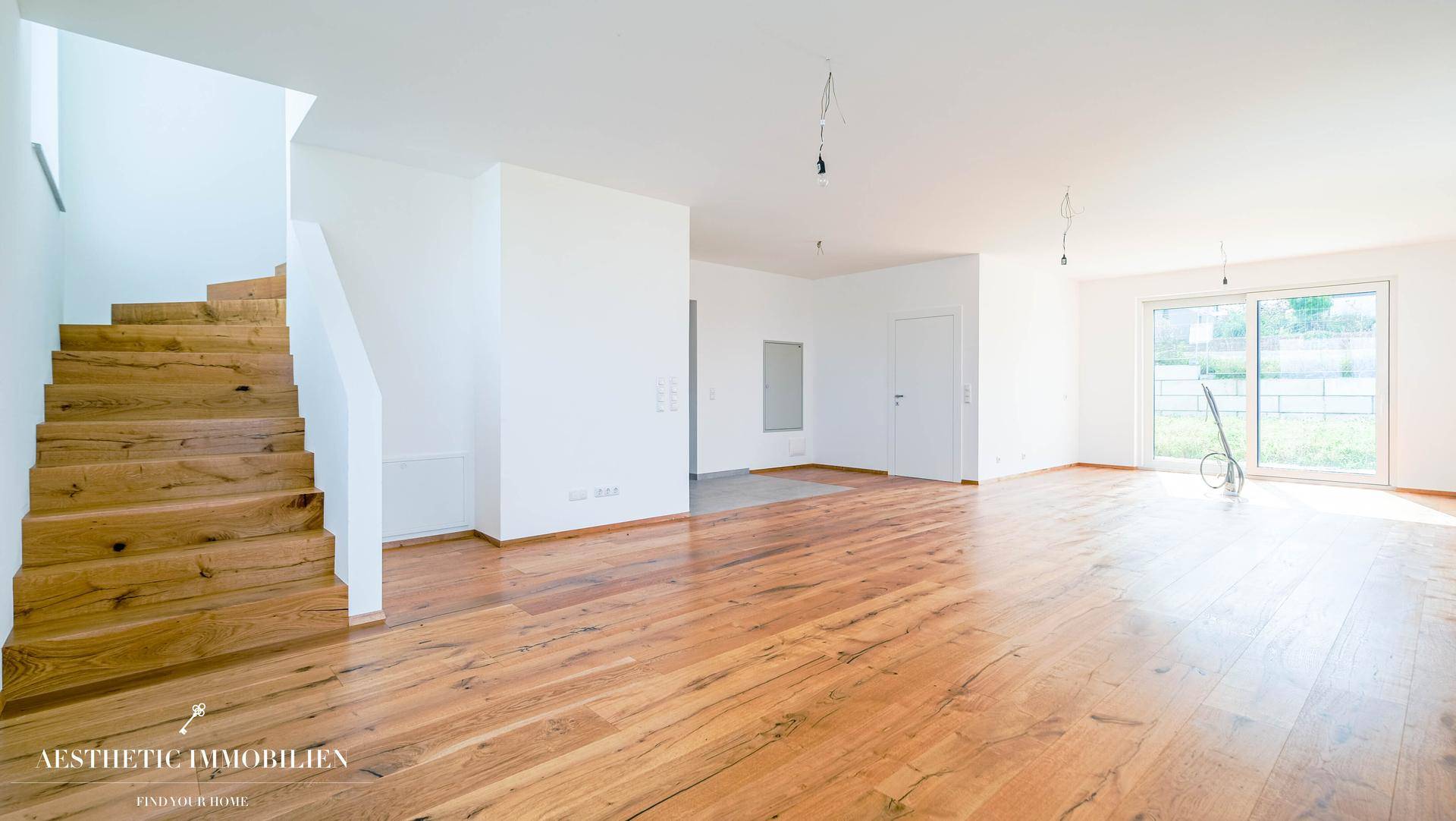 Geräumiger Eingangsbereich mit Holztreppe und hellem Holzboden, offen gestaltet.