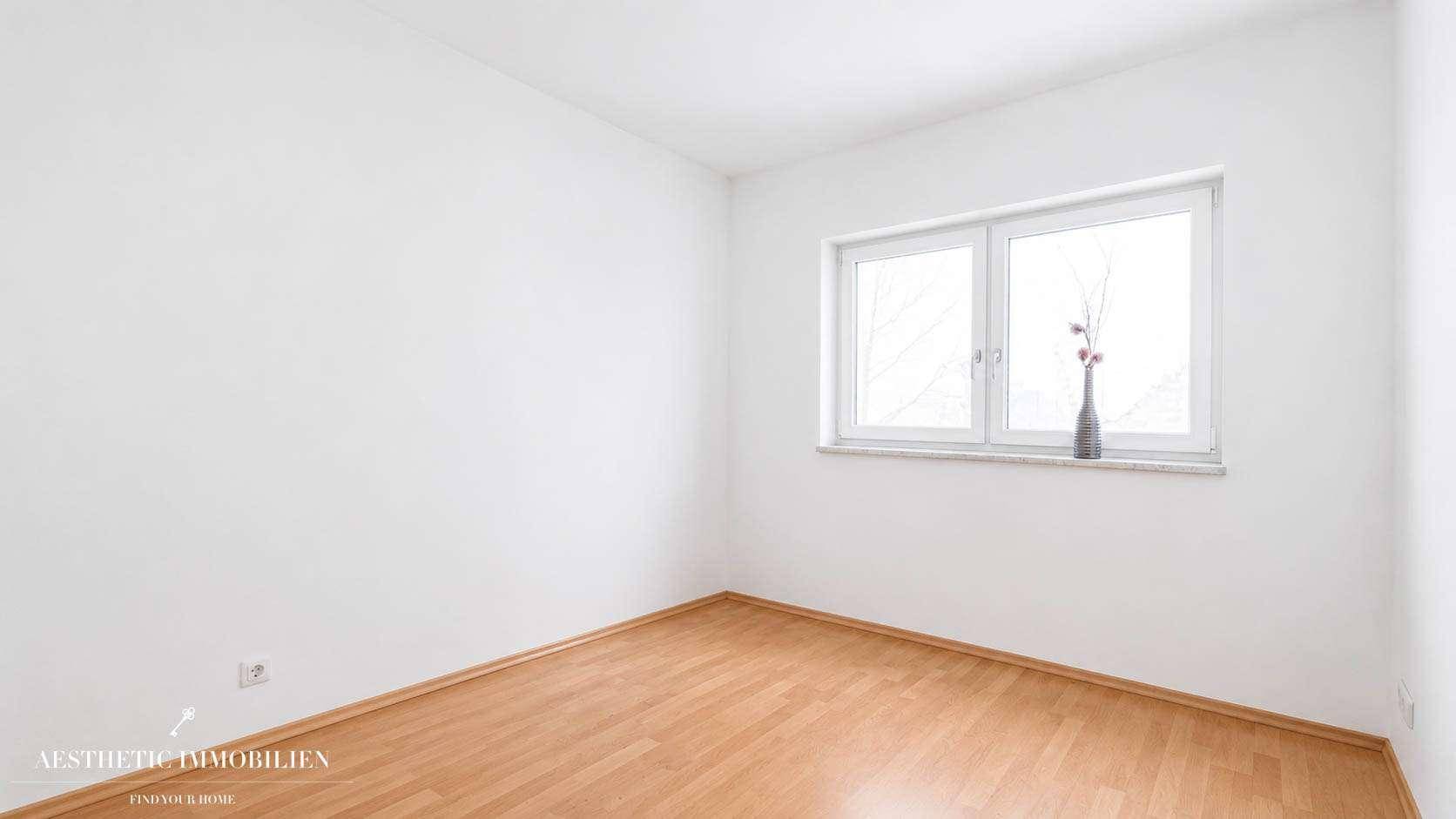 Leeres Zimmer mit hellem Holzboden, weißen Wänden und einem Fenster, ideal als Schlaf- oder Arbeitszimmer.