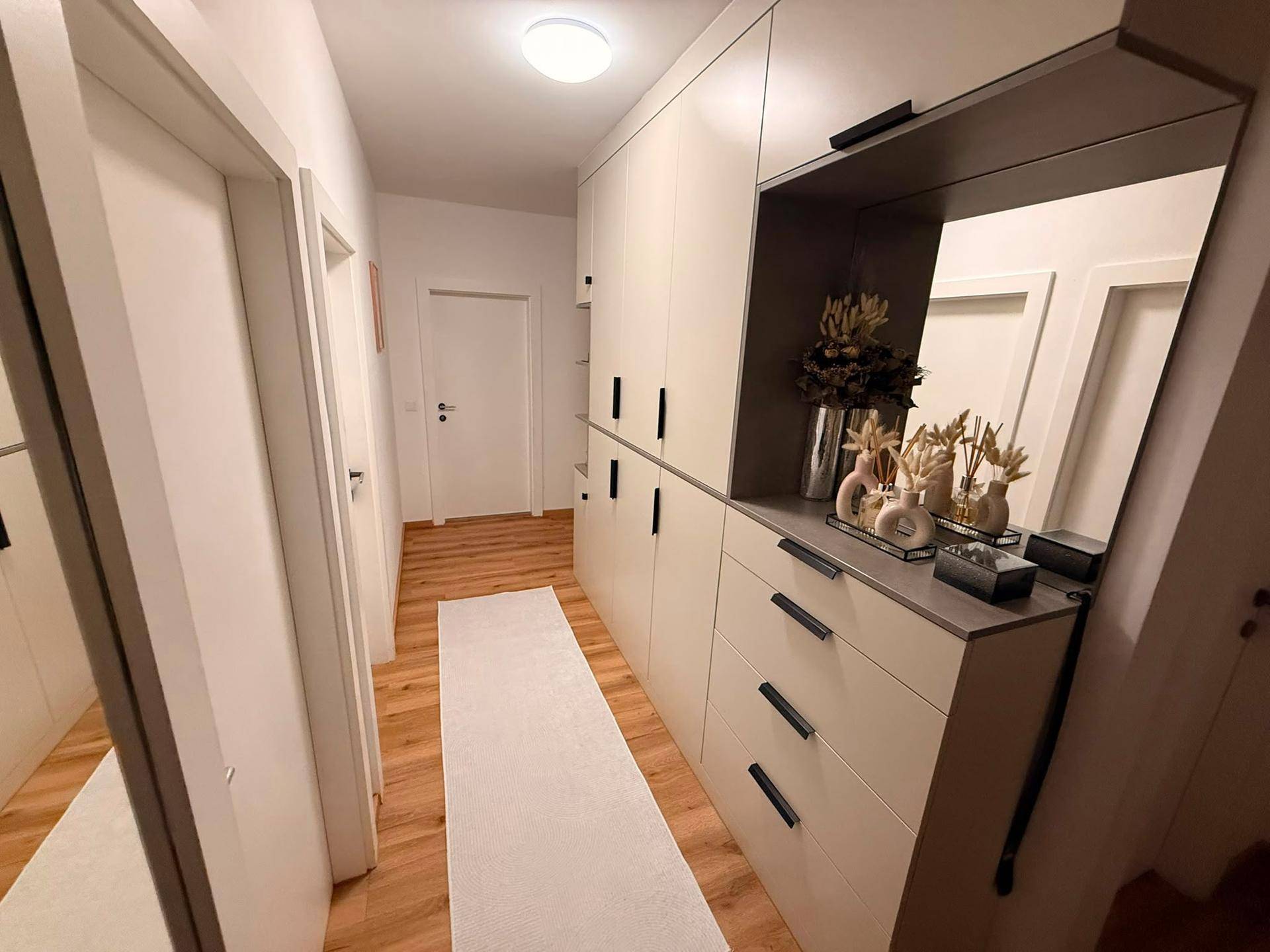 Heller Flur mit integriertem Spiegel, Einbauschränken und warmem Holzfußboden.