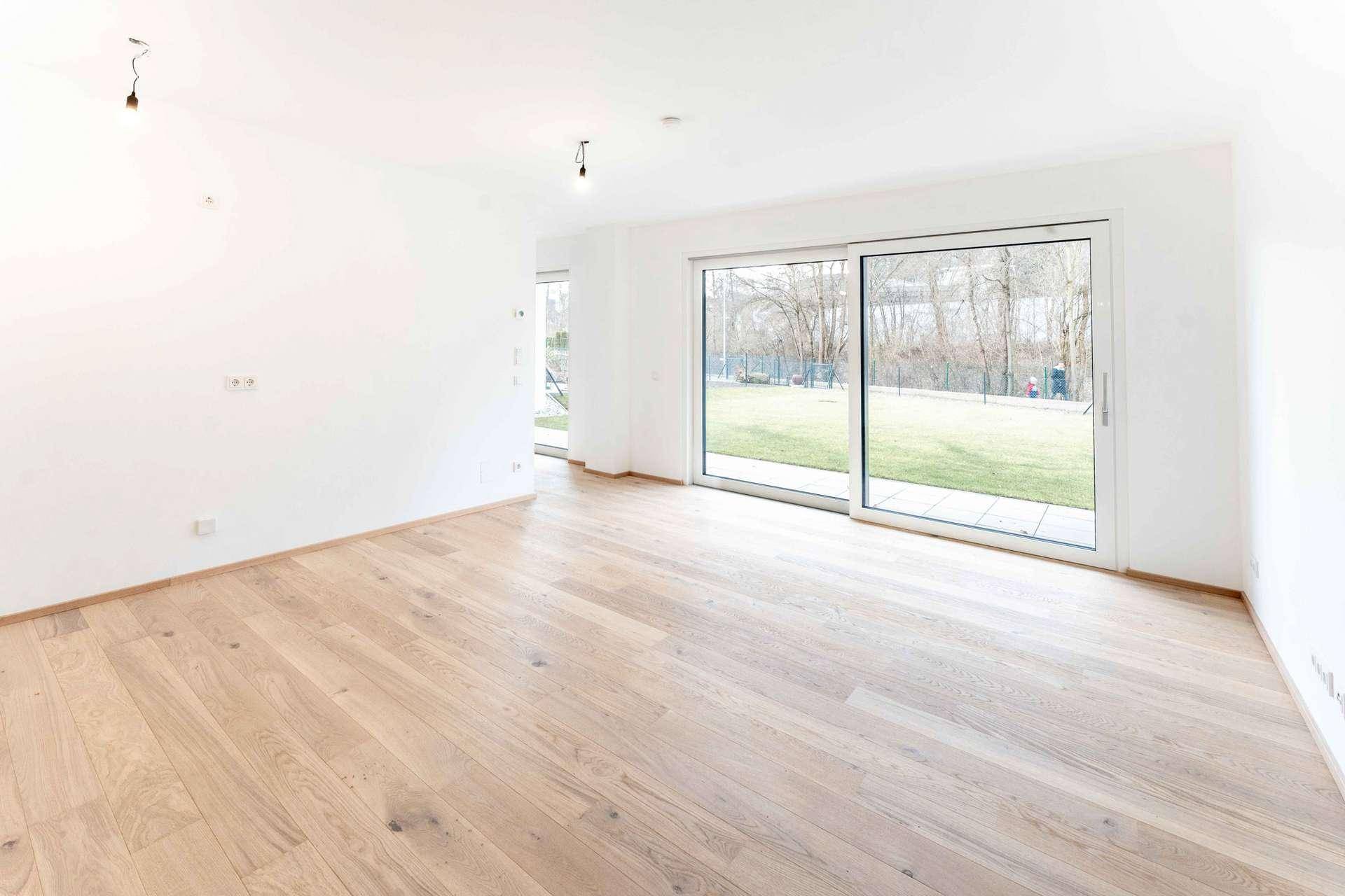 Geräumiges Wohnzimmer mit Holzboden und direktem Zugang zum privaten Gartenbereich.