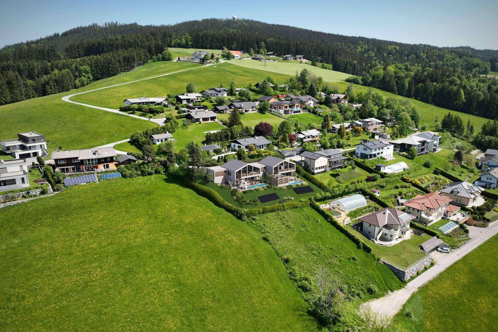 Weitläufige Luftaufnahme der modernen Villen, eingebettet in eine idyllische ländliche Umgebung mit viel Grün.