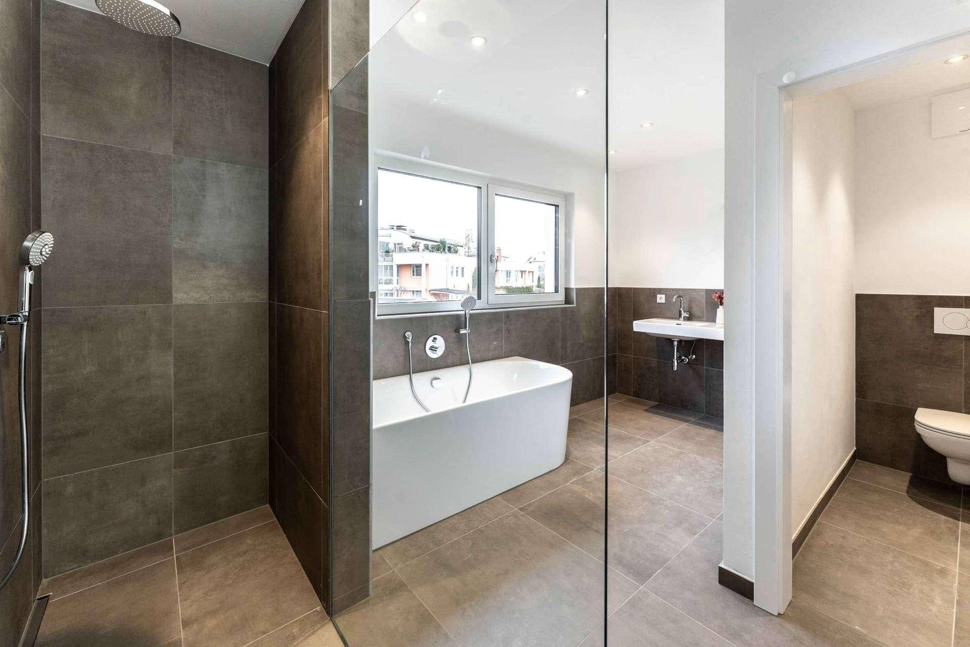 Elegantes Badezimmer mit moderner Dusche, Badewanne, Waschbecken und WC, hell gefliest.
