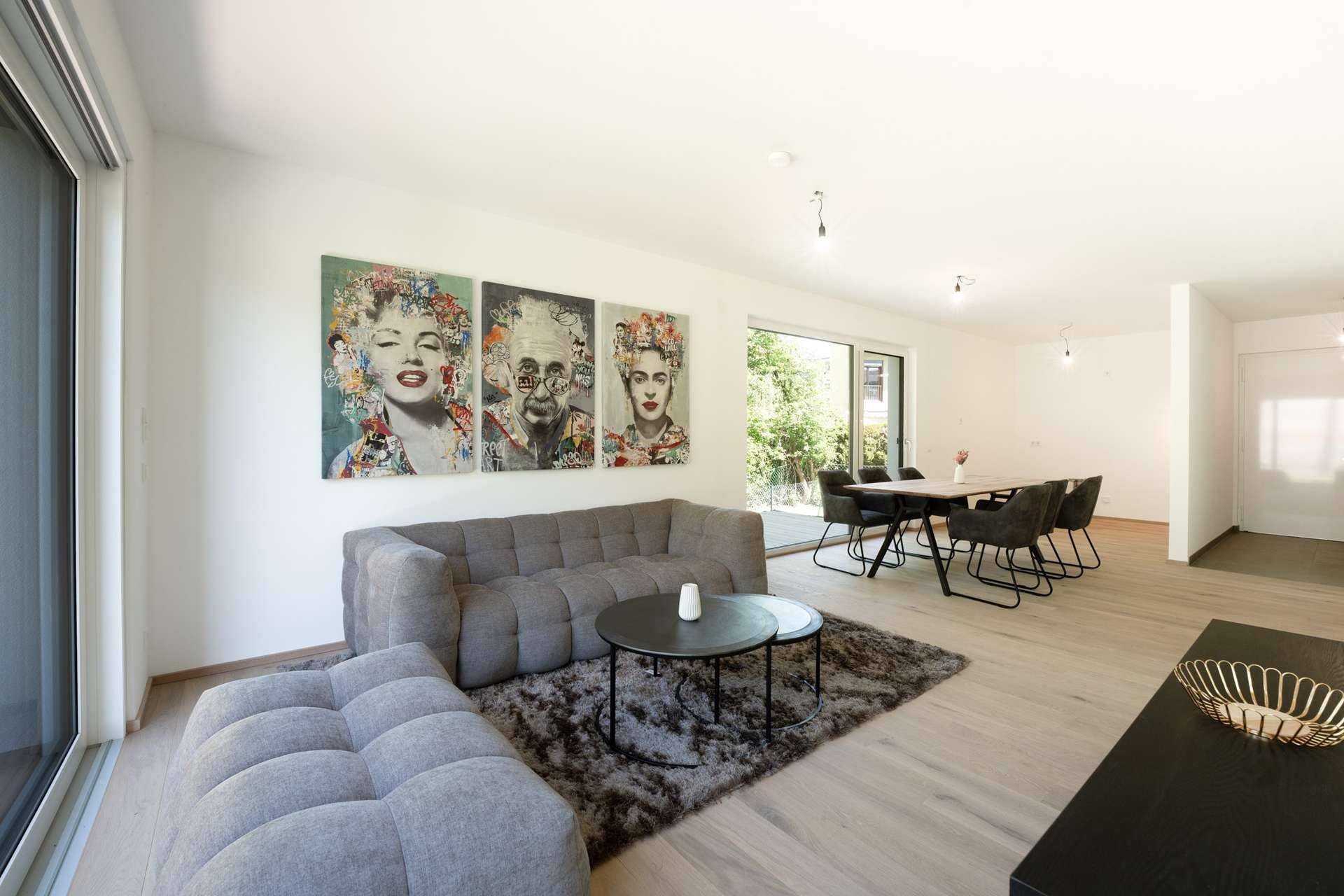 Geräumiger Wohn-Essbereich mit modernem Sofa, Esstisch und farbenfroher Wandkunst.