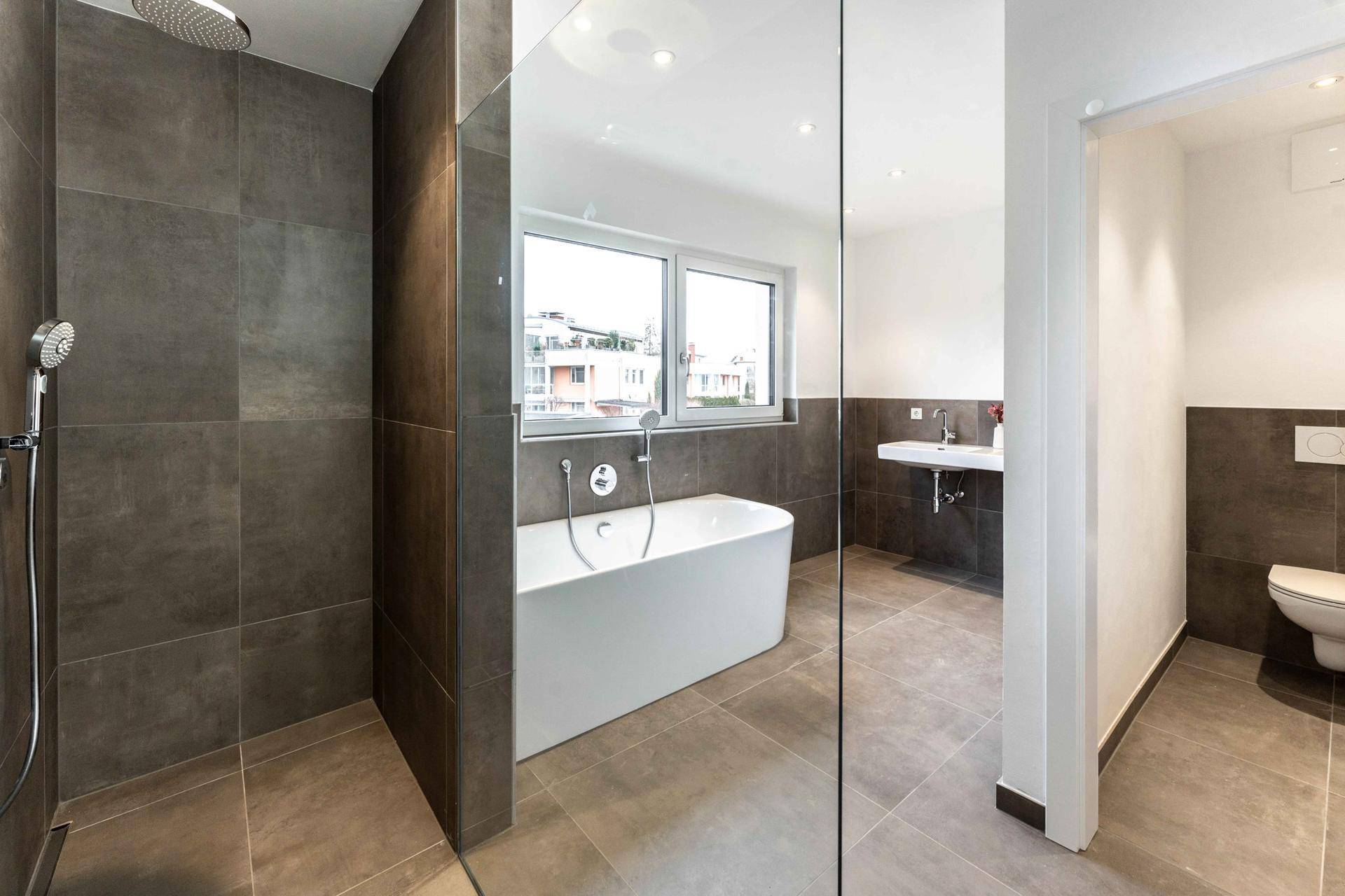 Modernes Badezimmer mit großer Badewanne, Dusche und Fenster.