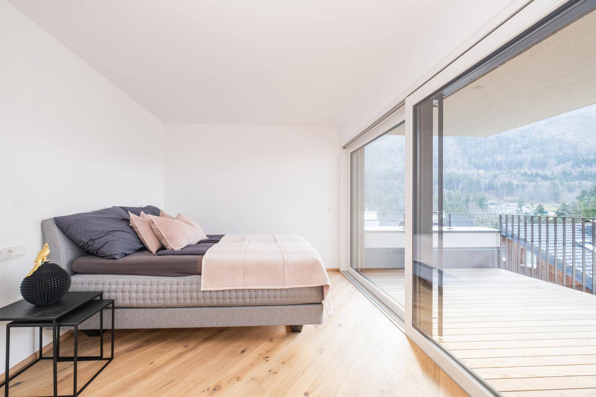Modernes Schlafzimmer mit Holzboden, großen Schiebetüren und direktem Zugang zur Terrasse.