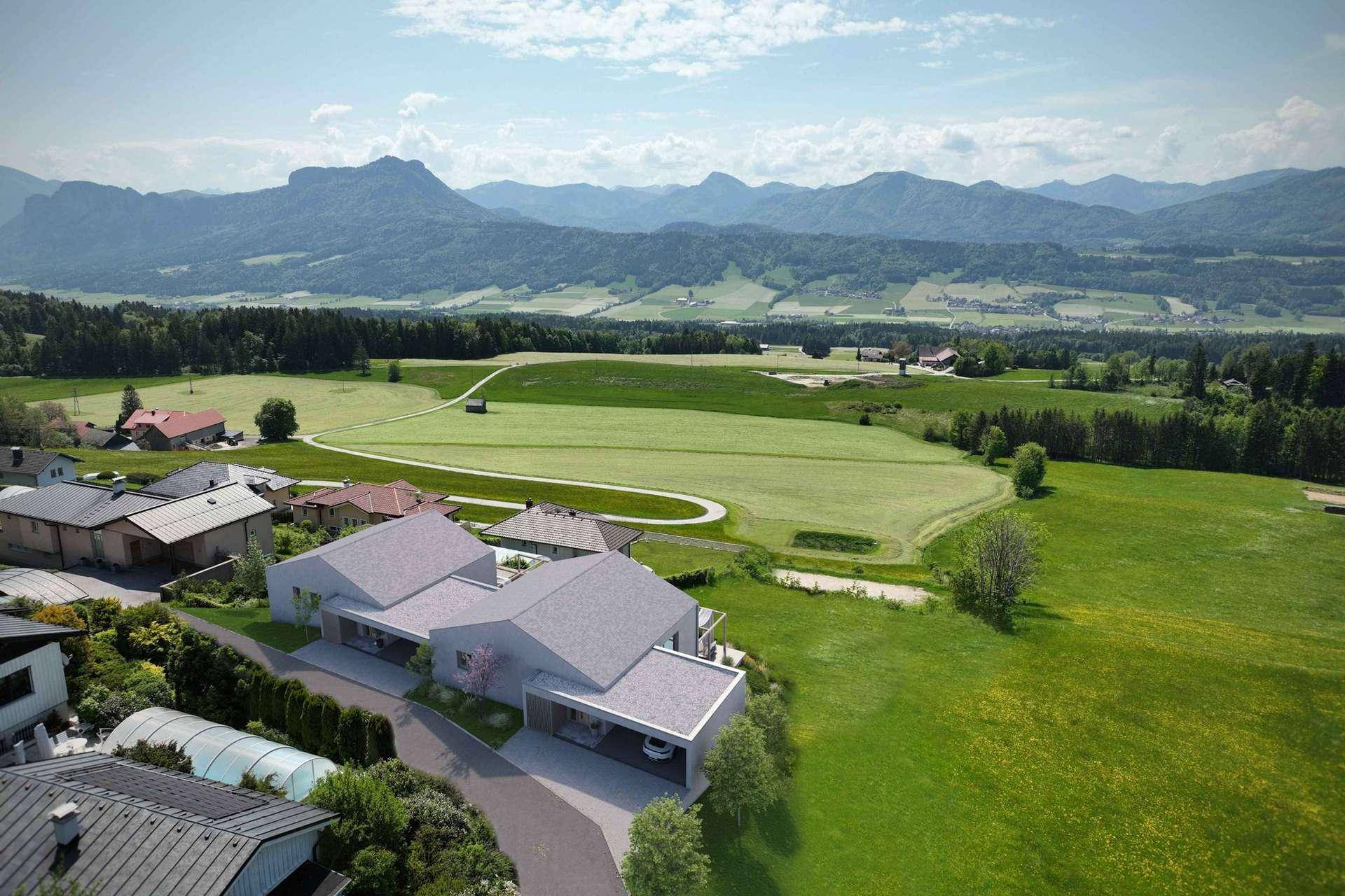 Eine moderne Villa mit Auffahrt und Bergblick, harmonisch in die weite grüne Landschaft integriert.
