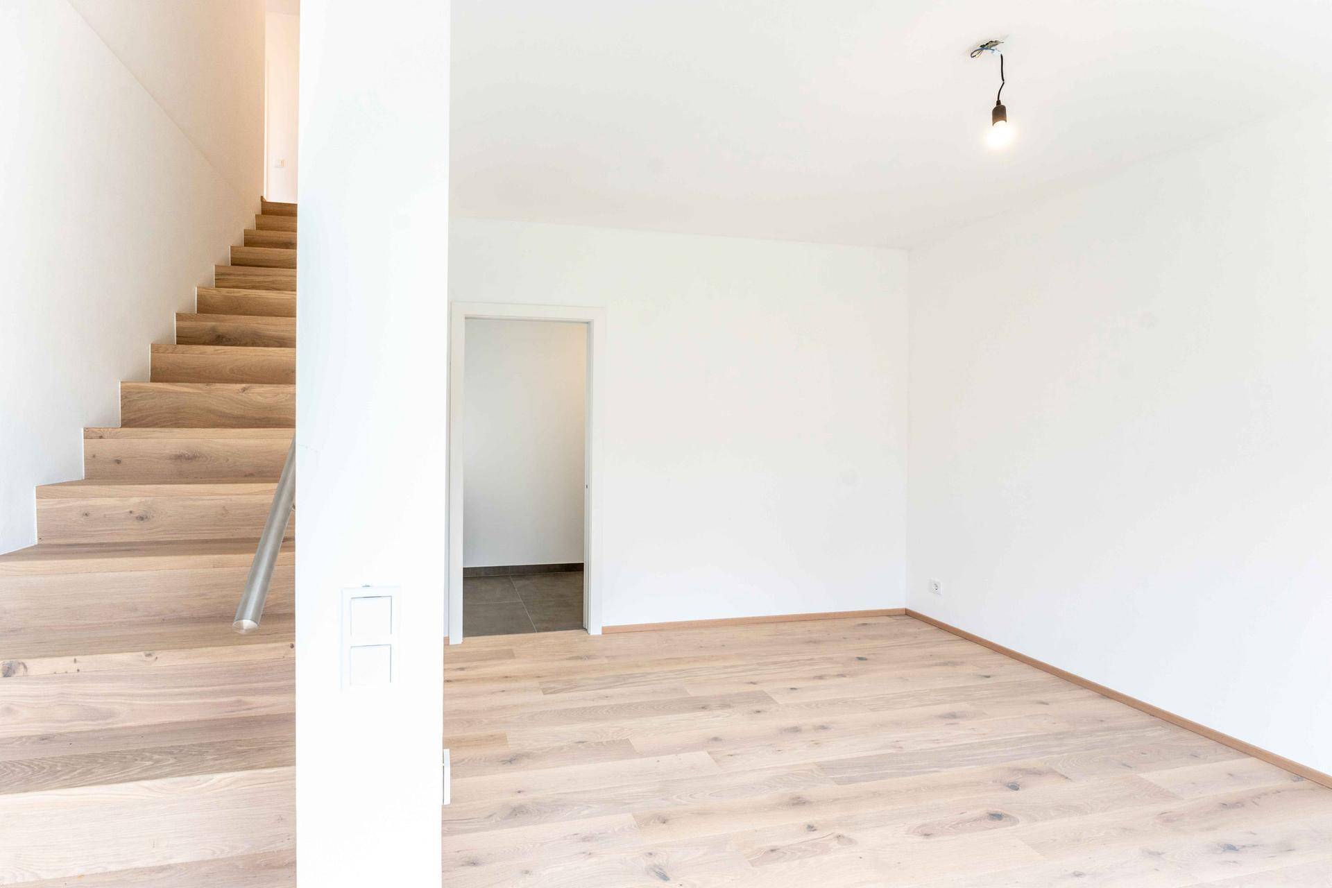 Heller Eingangsbereich mit Holztreppe und Parkettboden.
