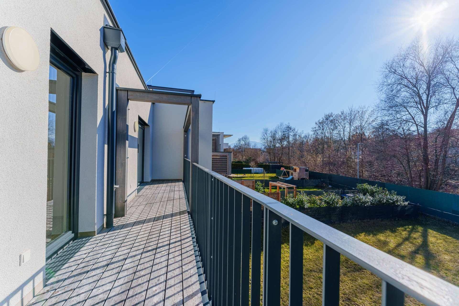 Geräumiger Balkon mit Holzboden und Blick ins Grüne, ideal für entspannte Stunden.