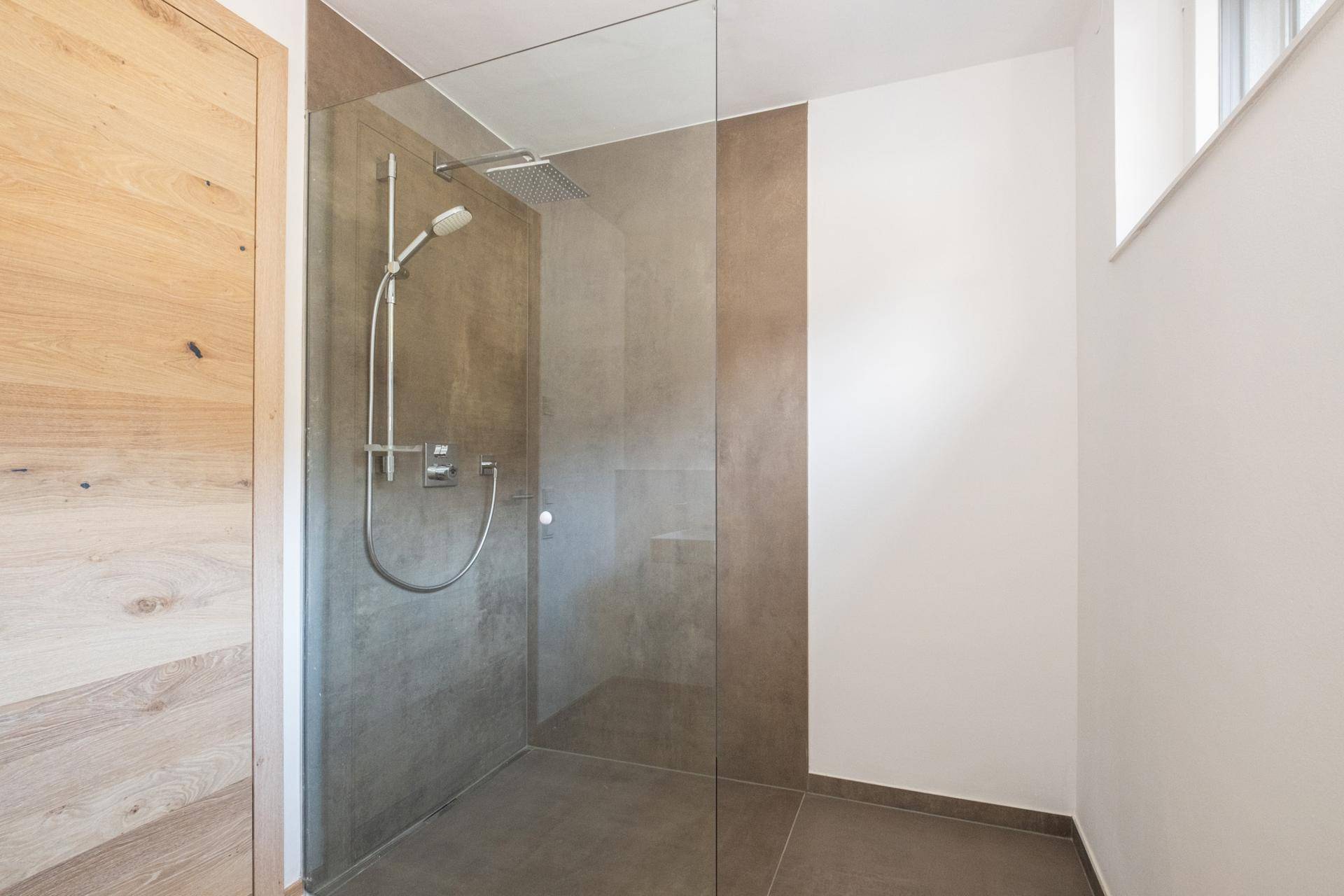 Geräumige, moderne Dusche mit Glasabtrennung und Regenduschkopf in einem hellen Badezimmer.