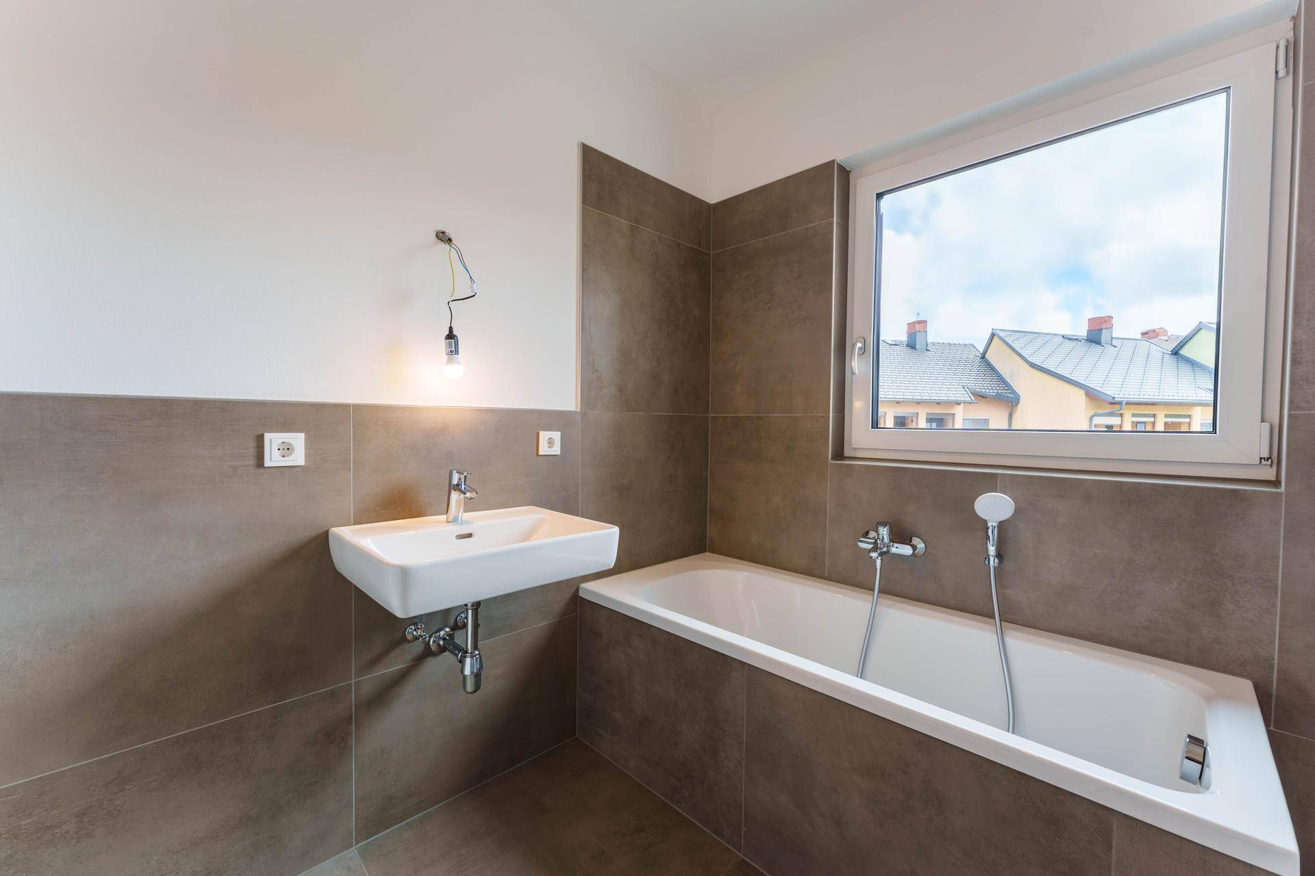 Modernes Badezimmer mit Badewanne, Waschbecken und Fenster für Tageslicht.