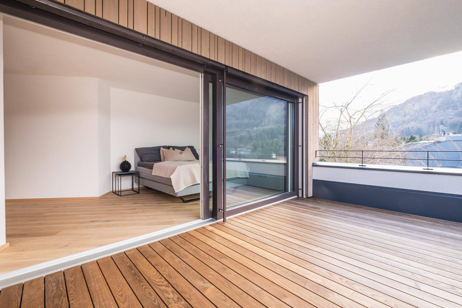 Helles Schlafzimmer mit Holzboden und direktem Zugang zu einem großen Balkon mit Bergblick.