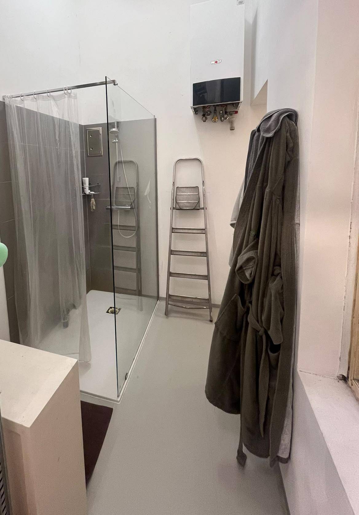 Modernes Badezimmer mit Glasduschkabine und Wandheizung in schlichtem Design.