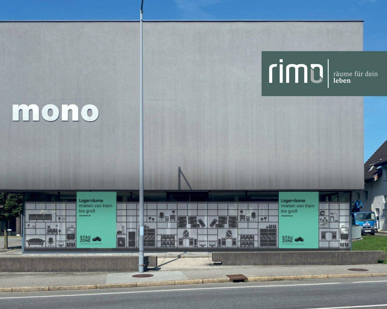 Gesamtansicht der modernen Gebäudefassade mit 'mono' Schriftzug und Lagerraum-Werbung im unteren Bereich.