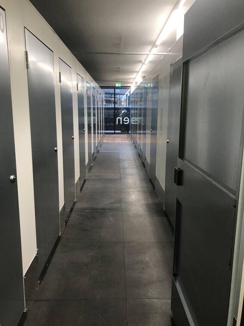Langer Flur mit zahlreichen Lagereinheiten und modernen Metalltüren, beleuchtet von Deckenleuchten.