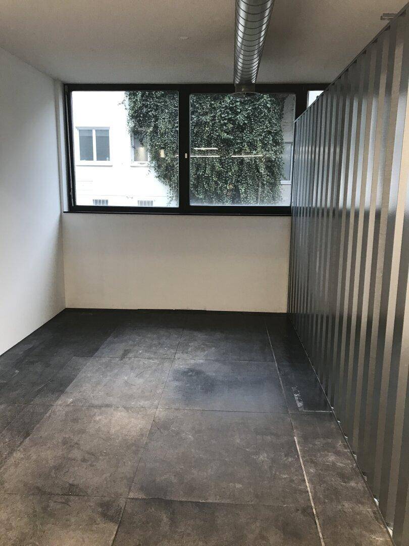 Lagereinheit mit Fenster, das einen Blick ins Grüne bietet, und dunklem Fliesenboden.