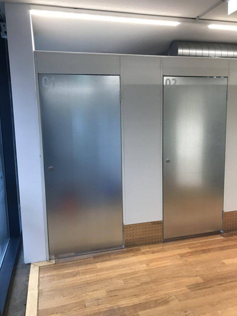 Zwei nummerierte Lagereinheiten mit Metalltüren in einem Flur mit Holzfußboden und großem Fenster.