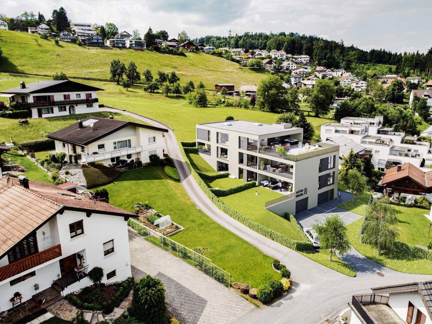 Luftaufnahme eines modernen Wohngebäudes in einer grünen, hügeligen Wohngegend.