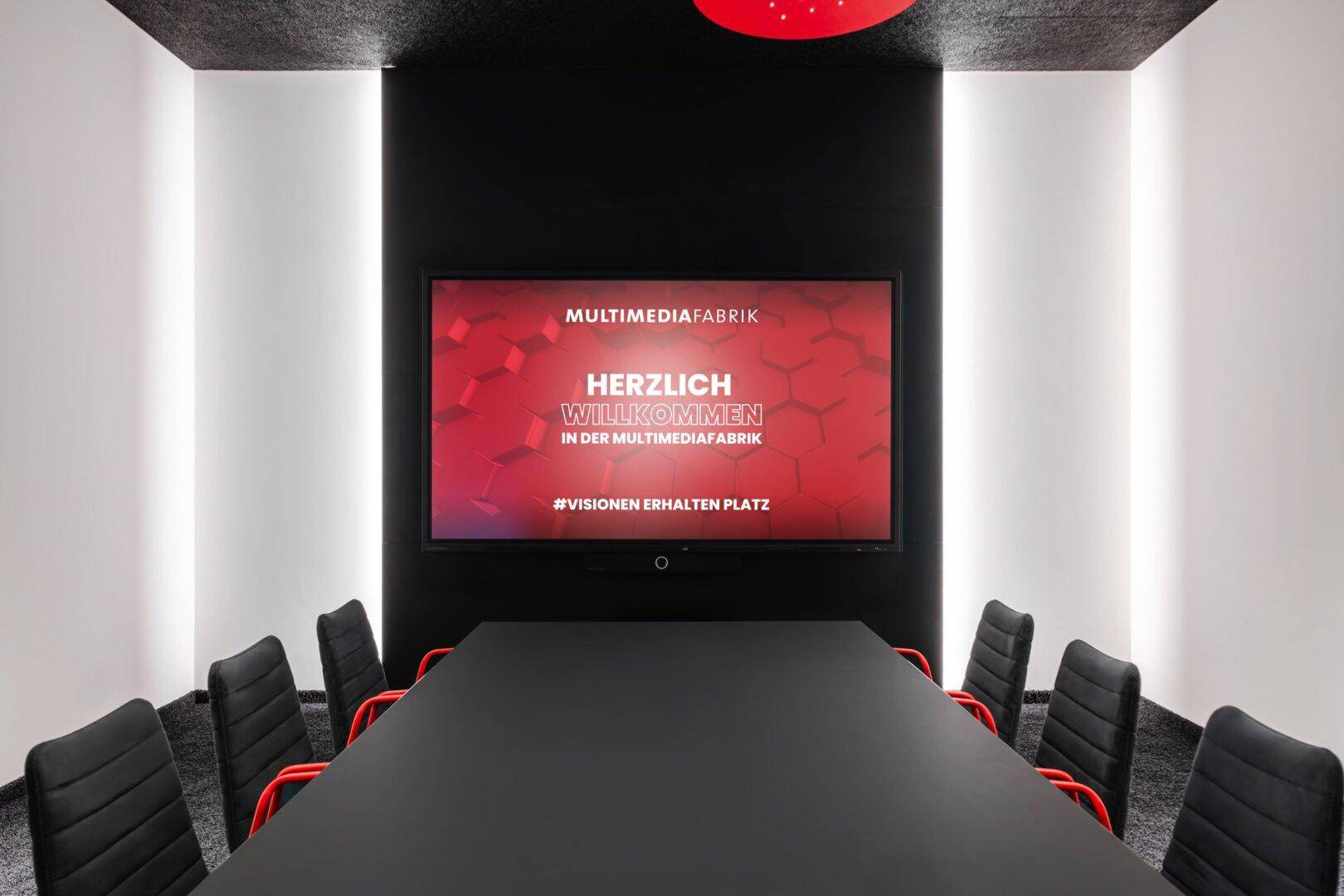 Konferenzraum mit langem, schwarzem Tisch und modernen Stühlen, ideal für geschäftliche Besprechungen.