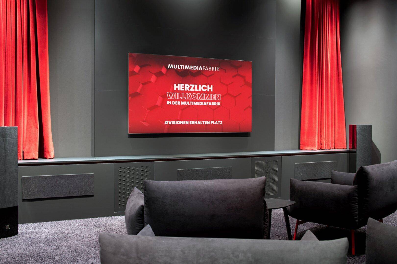 Dunkler Medienraum mit großem Bildschirm, bequemen Sofas und roten Vorhängen für eine immersive Atmosphäre.