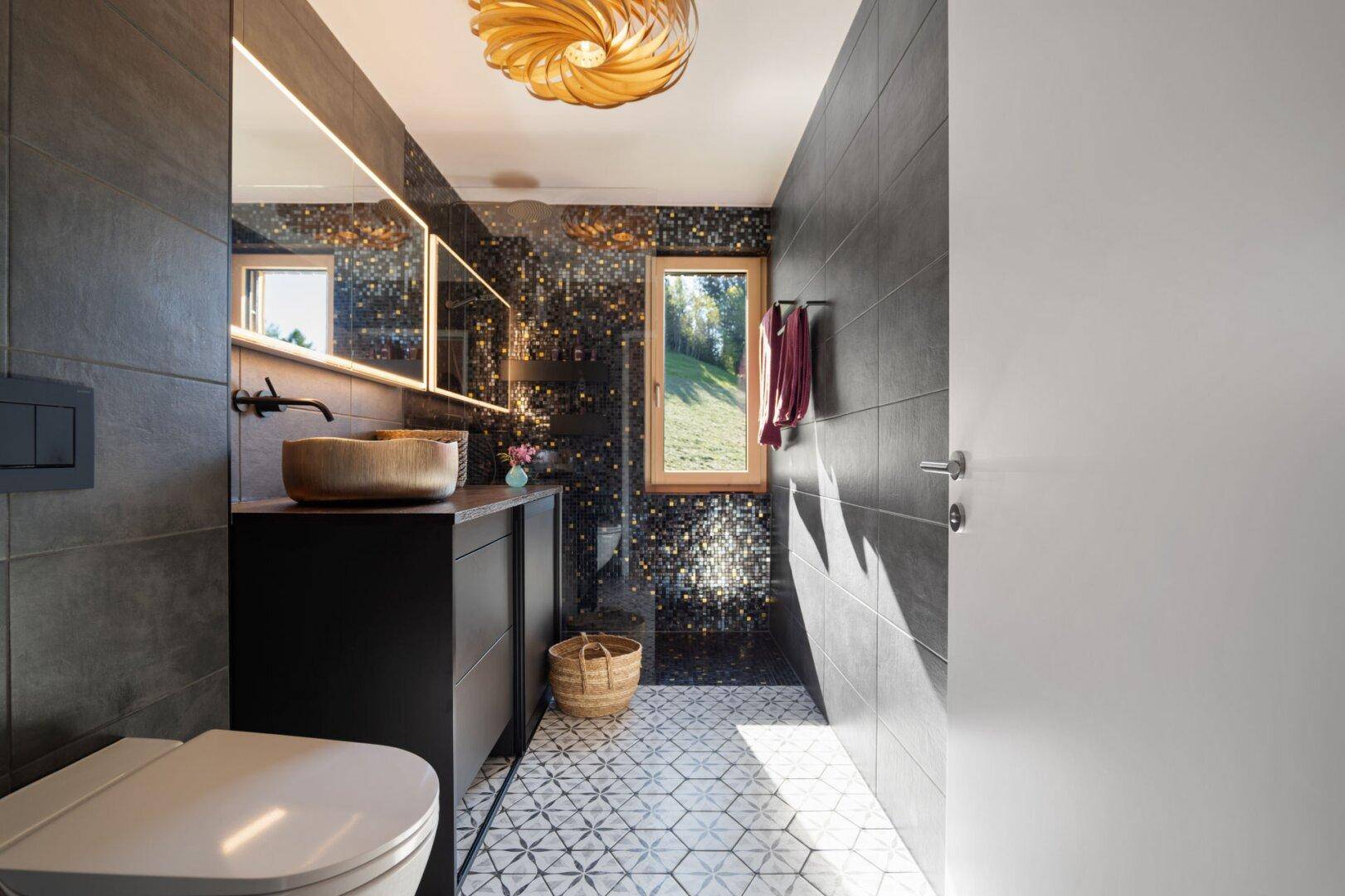 Stilvolles Badezimmer mit dunklen Wandfliesen, gemustertem Boden und modernem WC.